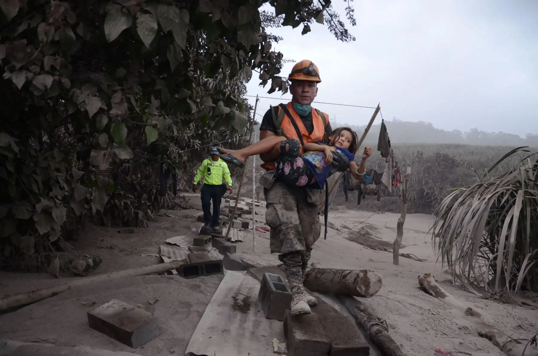Un trabajador de los equipos de rescate de Guatemala ayuda a una niña en El Rodeo, Escuintla (Guatemala). Foto: Efe.