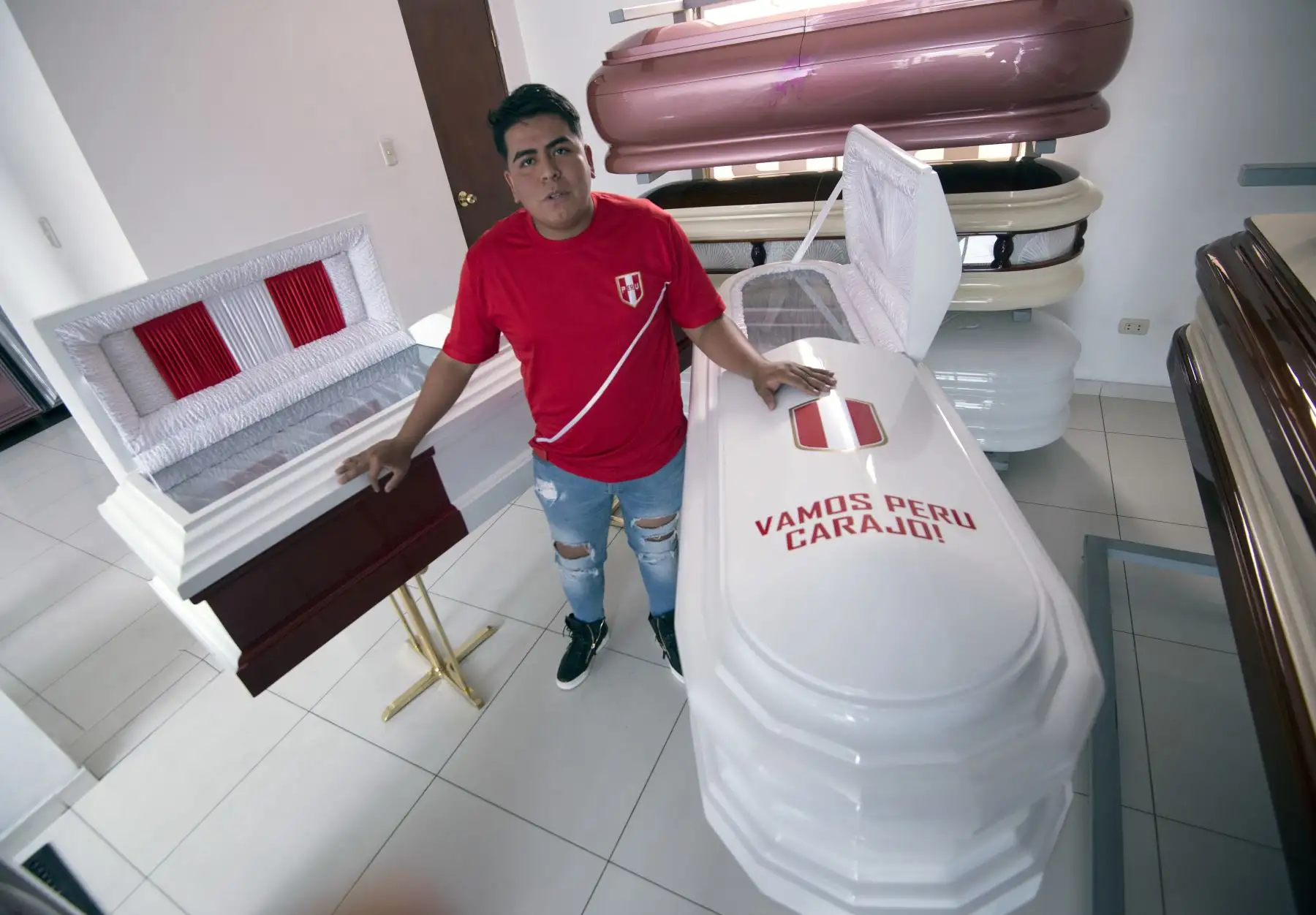 Funeraria Galindo ofrece servicios de entierro  en el popular barrio de San Juan de Lurigancho, en un coche fúnebre decorado con los colores del equipo nacional de fútbol, y ataúdes también pintados en blanco y rojo con la frase 