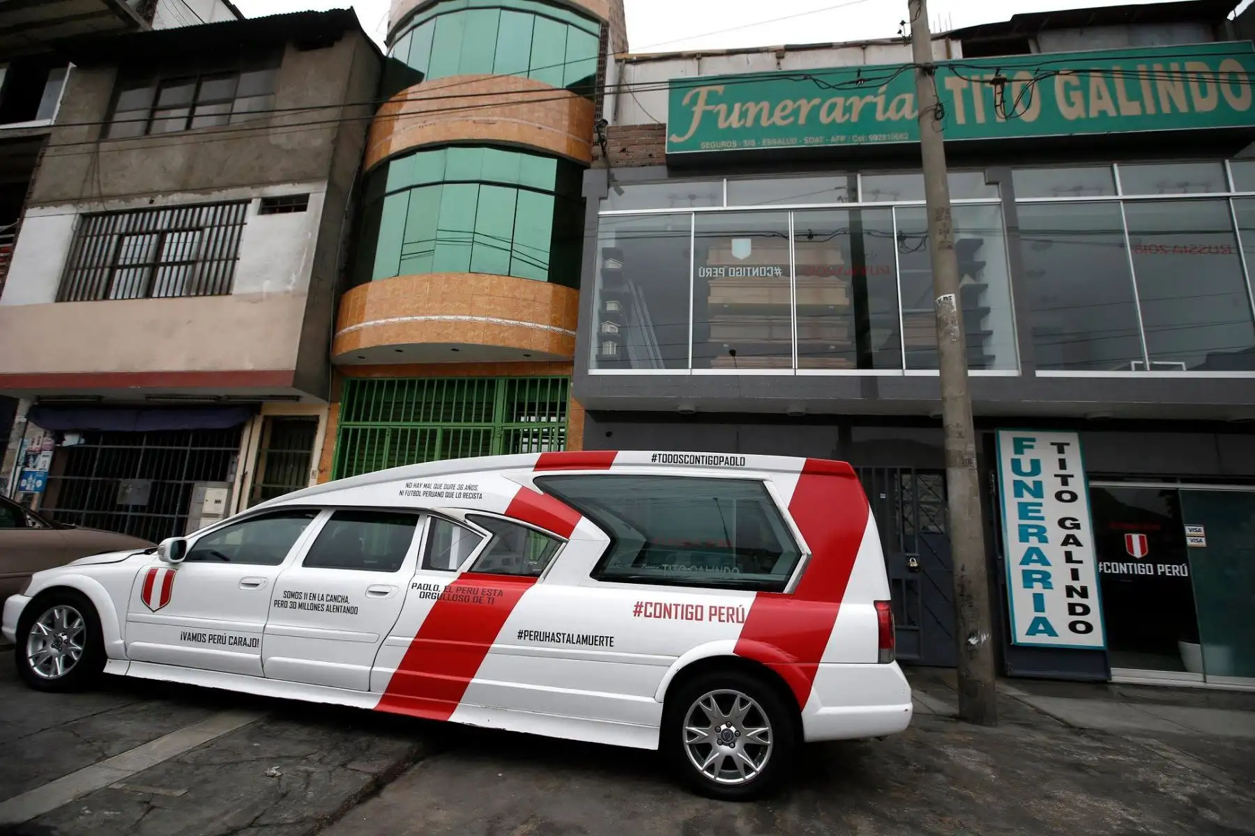 Funeraria Galindo ofrece servicios de entierro  en el popular barrio de San Juan de Lurigancho, en un coche fúnebre decorado con los colores del equipo nacional de fútbol, y ataúdes también pintados en blanco y rojo con la frase 