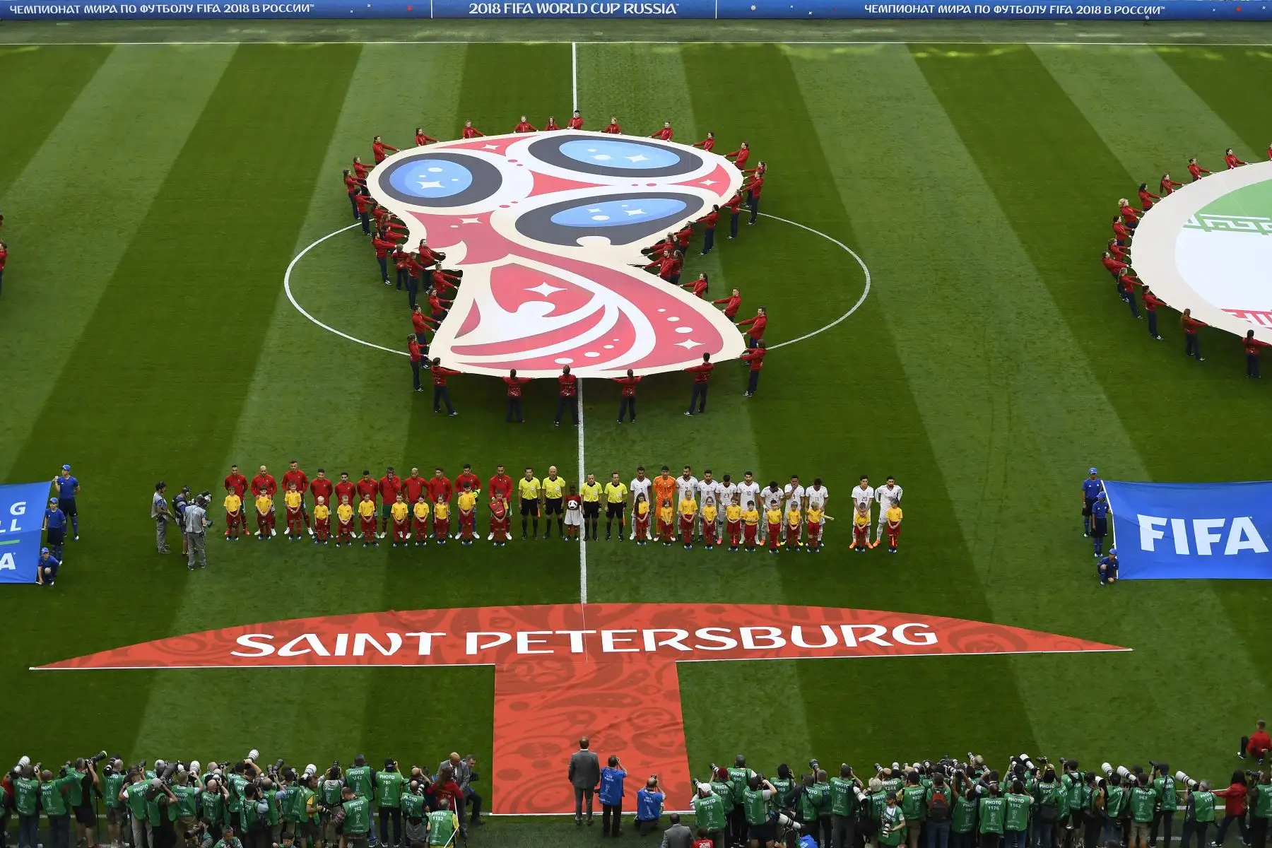 Los voluntarios exhiben el logo de la Copa Mundial en el terreno de juego antes del partido de fútbol del Grupo B de la Copa Mundial Rusia 2018 entre Marruecos e Irán en el Estadio de San Petersburgo. AFP