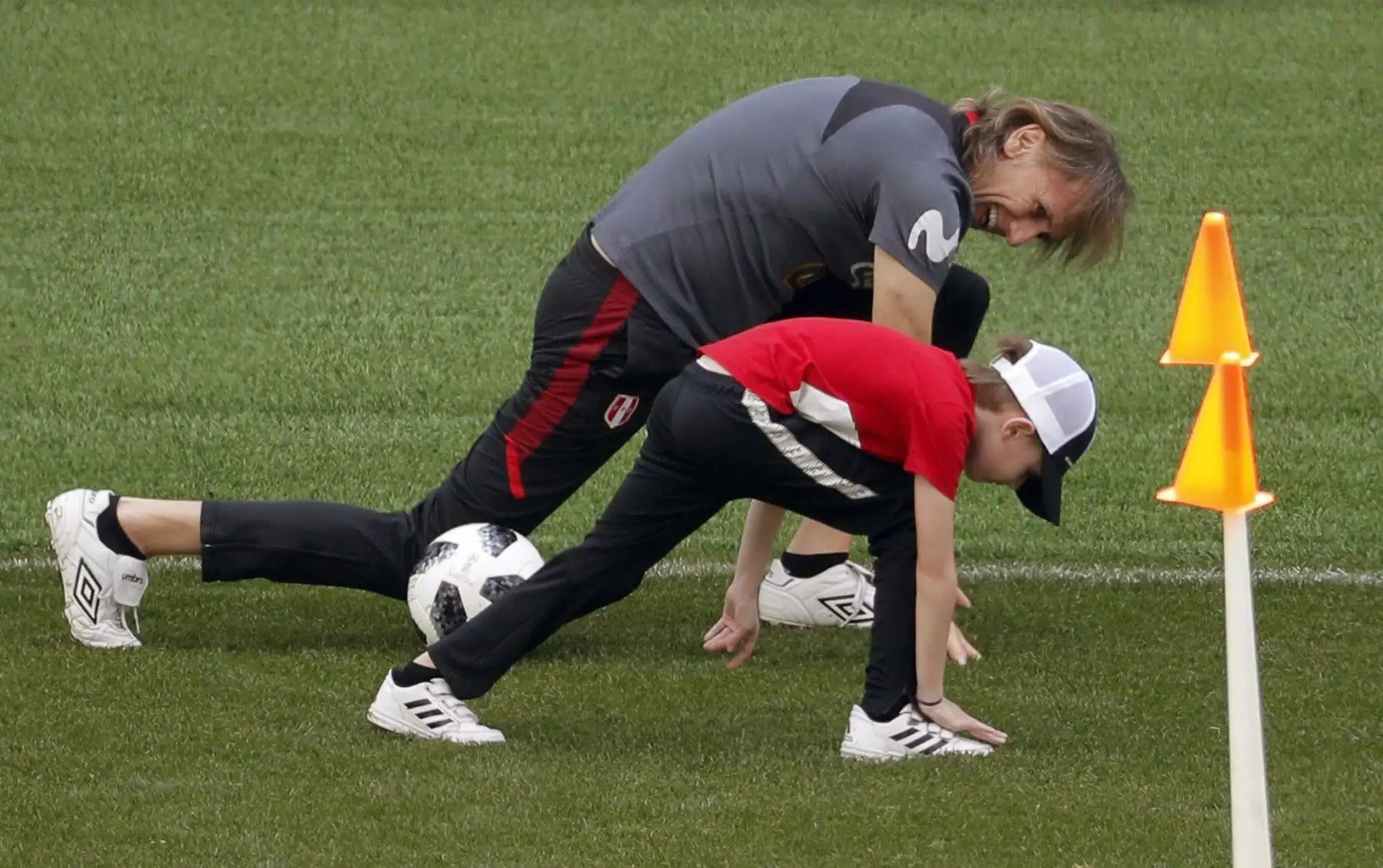 El DT Ricardo Gareca estira junto a su nieto Benjamín durante el entrenamiento de Perú, en el estadio Khimki de Moscú. Foto: EFE.