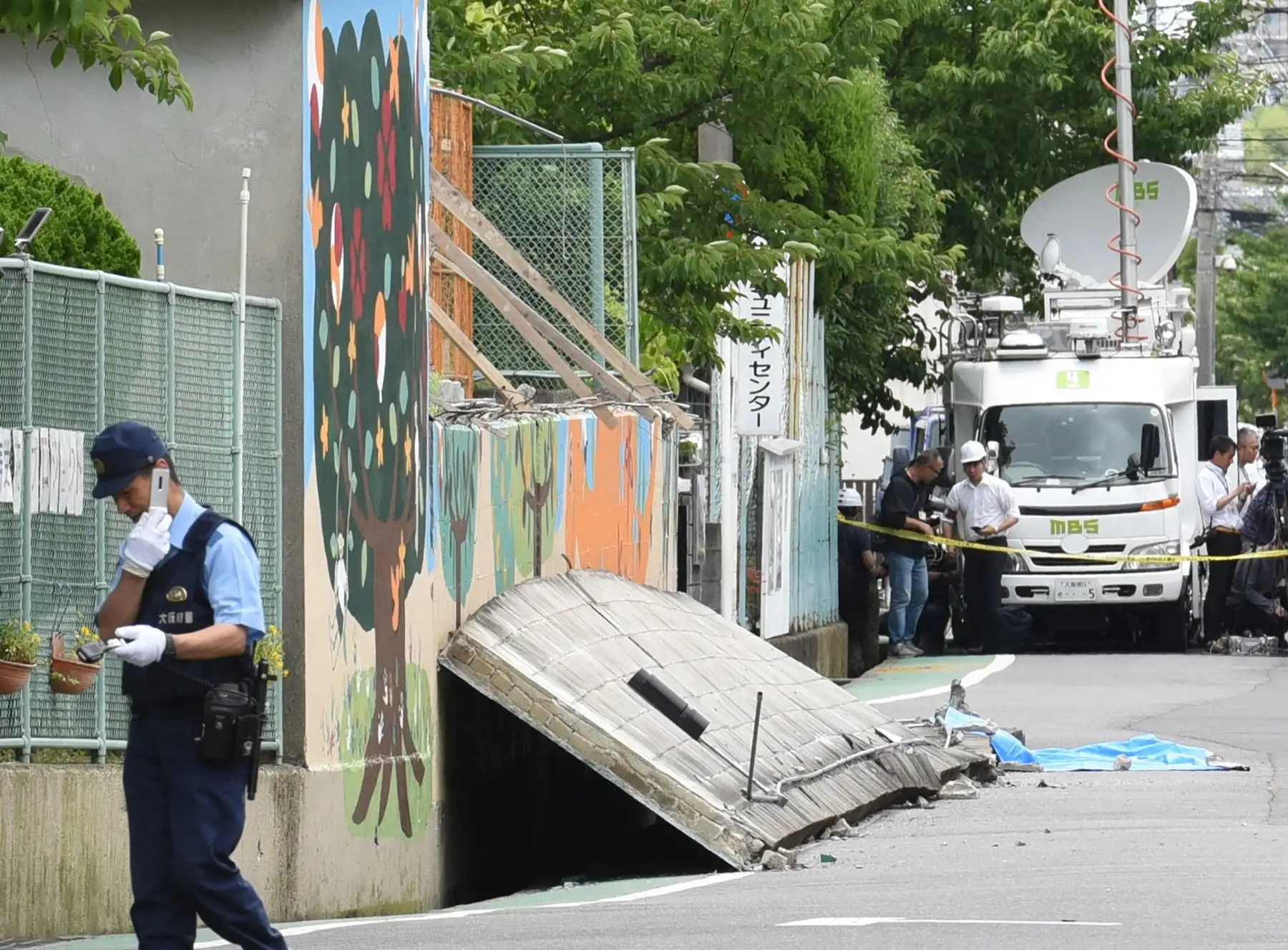 Un policía monta guardia cerca de una pared derrumbada donde murió una niña después de un terremoto en la ciudad de Takatsuki, al norte de la prefectura de Osaka. Foto:AFP
