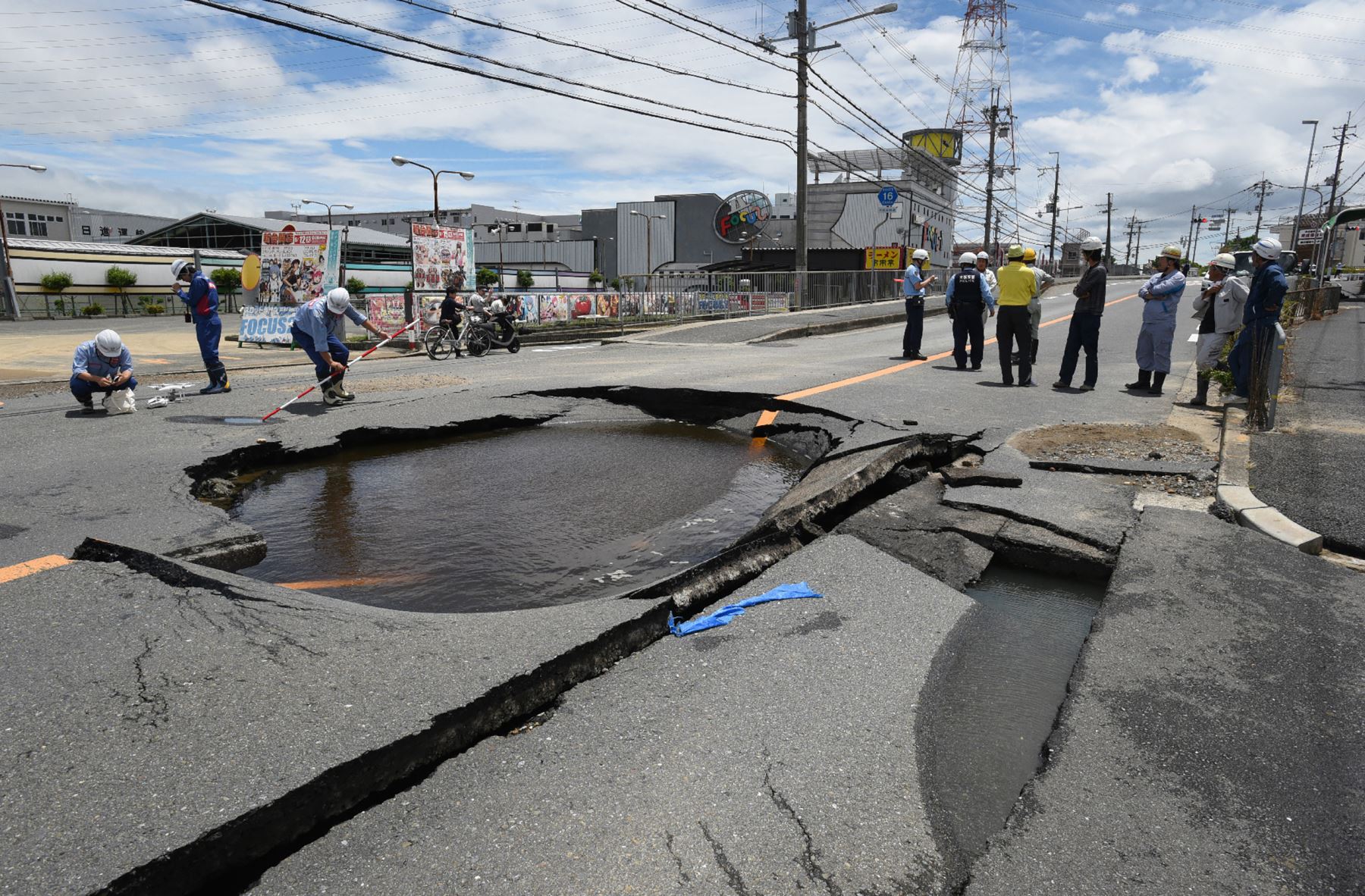 Los trabajadores permanecen junto a un camino parcialmente colapsado después de un terremoto en Takatsuki, al norte de la prefectura de Osaka . / AFP