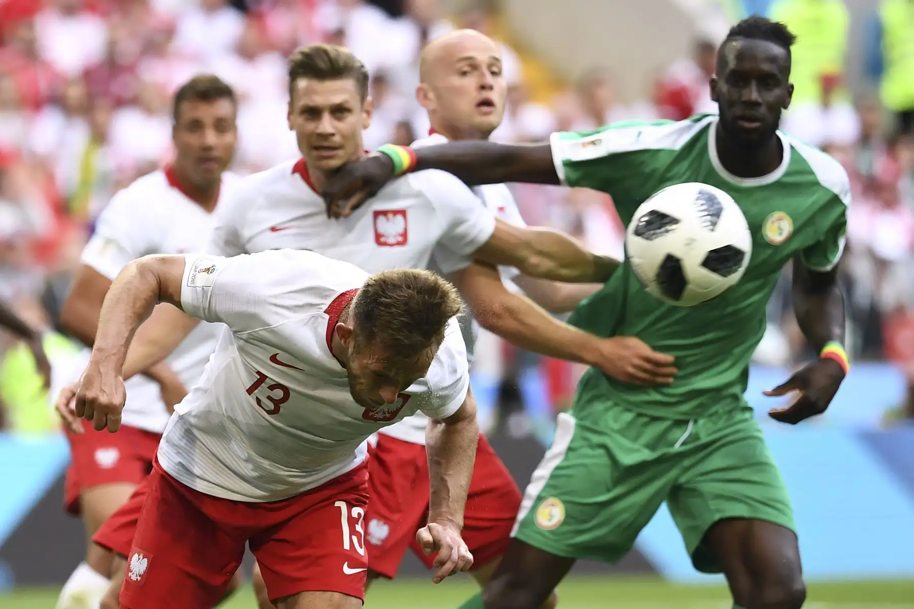 El centrocampista polaco Maciej Rybus (C) encabeza el balón junto al defensor polaco Lukasz Piszczek (parte trasera L) y el defensa senegalés Salif Sane (R) durante el partido de fútbol Rusia 2018 Grupo H entre Polonia y Senegal en el Spartak Stadium de Moscú en junio 19, 2018. / AFP
