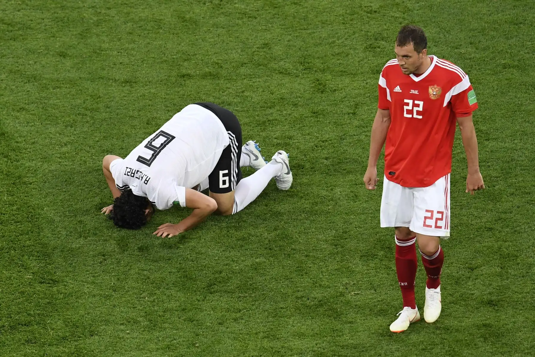 El delantero de Egipto Marwan Mohsen (izq.) Ora mientras el delantero ruso Artem Dzyuba (R) camina durante el partido de fútbol del Grupo A de la Copa Mundial Rusia 2018 entre Rusia y Egipto en el estadio de San Petersburgo el 19 de junio de 2018. / AFP
