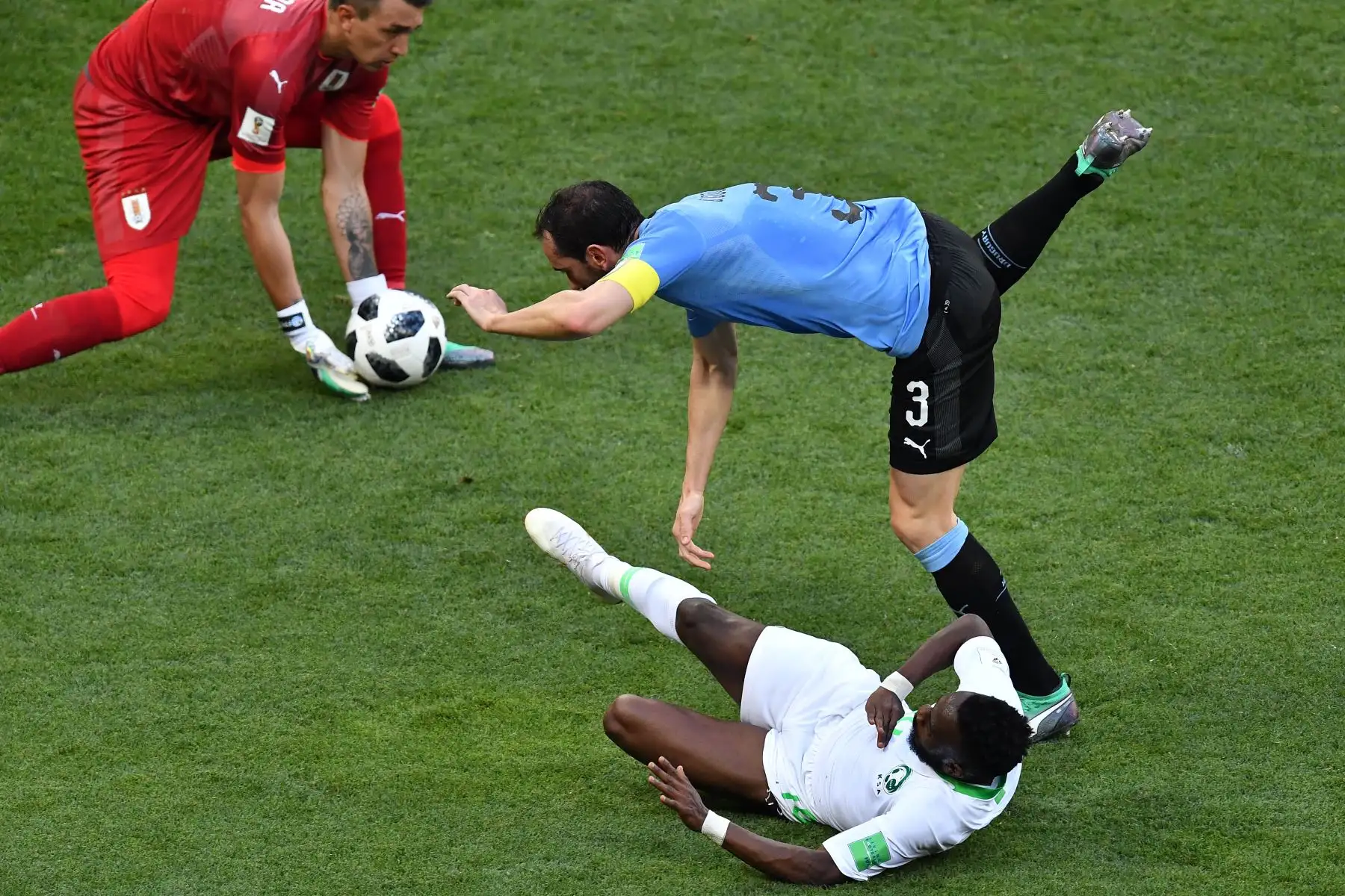 El delantero de Arabia Saudita Fahad Al-Muwallad (abajo) intenta anotar contra el arquero uruguayo Fernando Muslera (L) y el defensor uruguayo Diego Godin durante el partido de fútbol del Grupo A de Rusia 2018 entre Uruguay y Arabia Saudita en el Rostov Arena de Rostov-On- Don el 20 de junio de 2018. / AFP