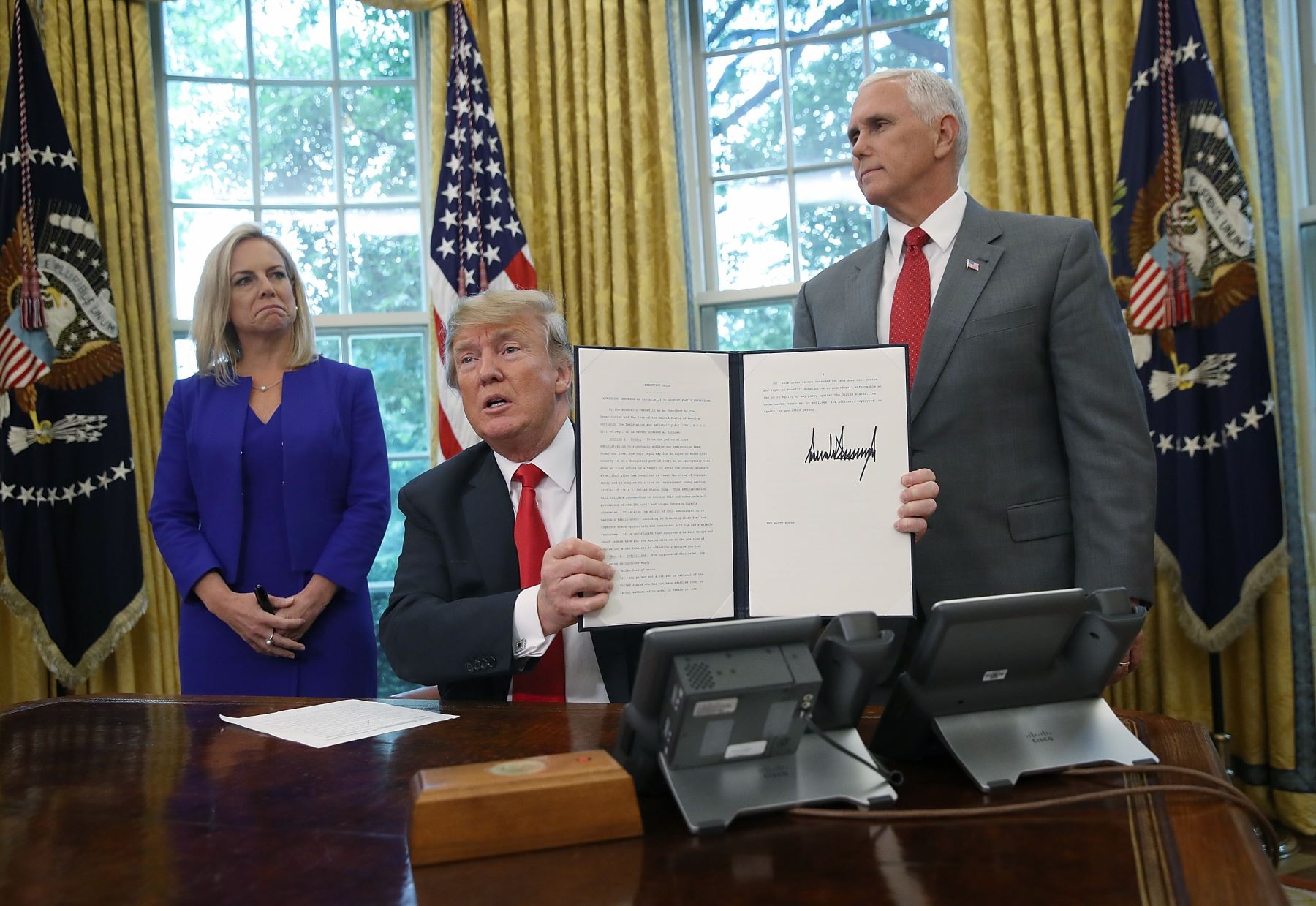 Trump, acompañado por la secretaria del Departamento de Seguridad Nacional Kirstjen Nielsen y el vicepresidente Mike Pence, firma el decreto que pone fin a separaciones familiares en la frontera Foto: AFP