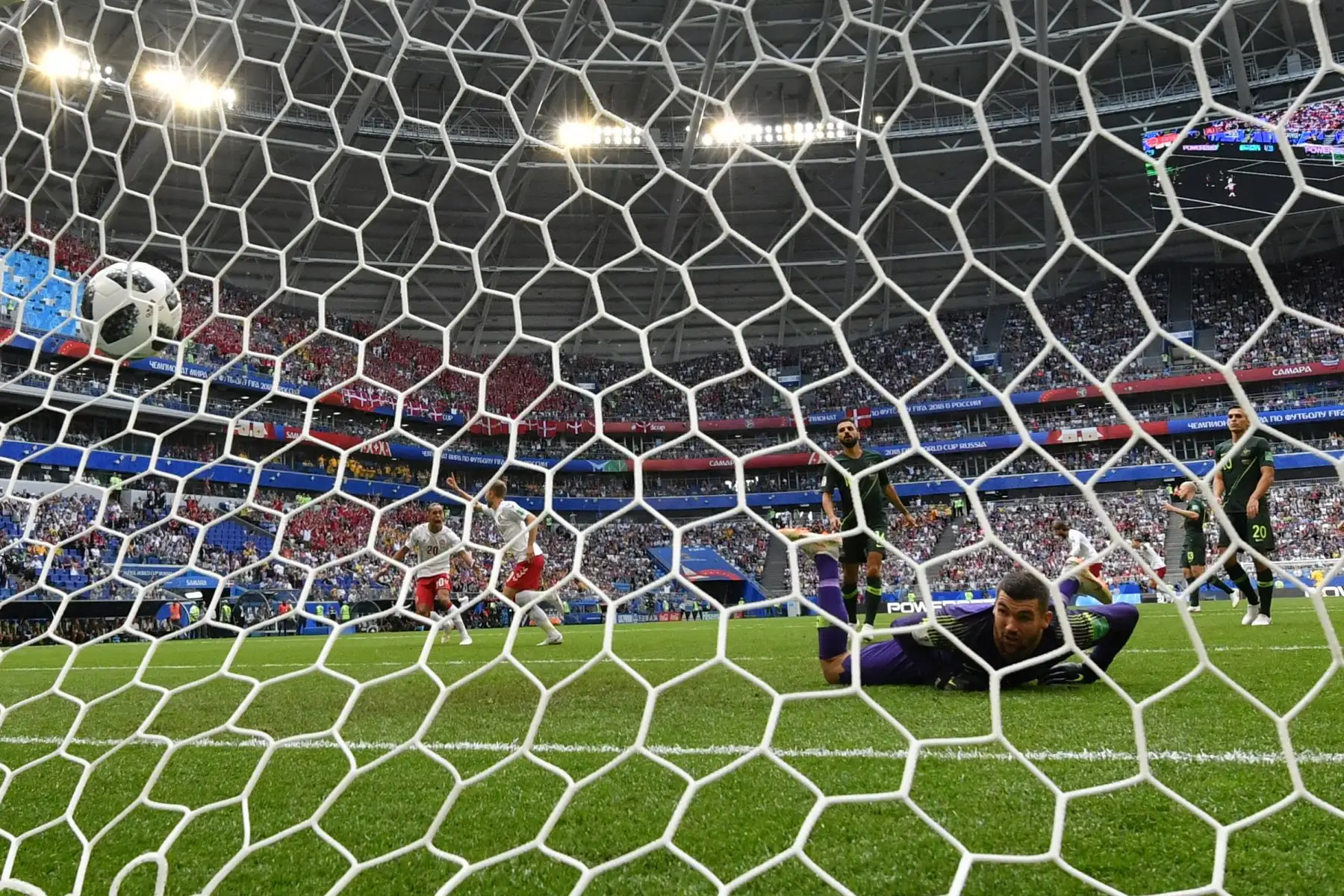 El balón golpea la parte posterior de la red después de vencer al portero australiano Mathew Ryan (R) por el primer gol de Dinamarca anotado por el centrocampista danés Christian Eriksen (2L) durante el partido de fútbol del Grupo C de la Copa Mundial Rusia 2018 entre Dinamarca y Australia en el Samara Arena de Samara el 21 de junio de 2018. / AFP