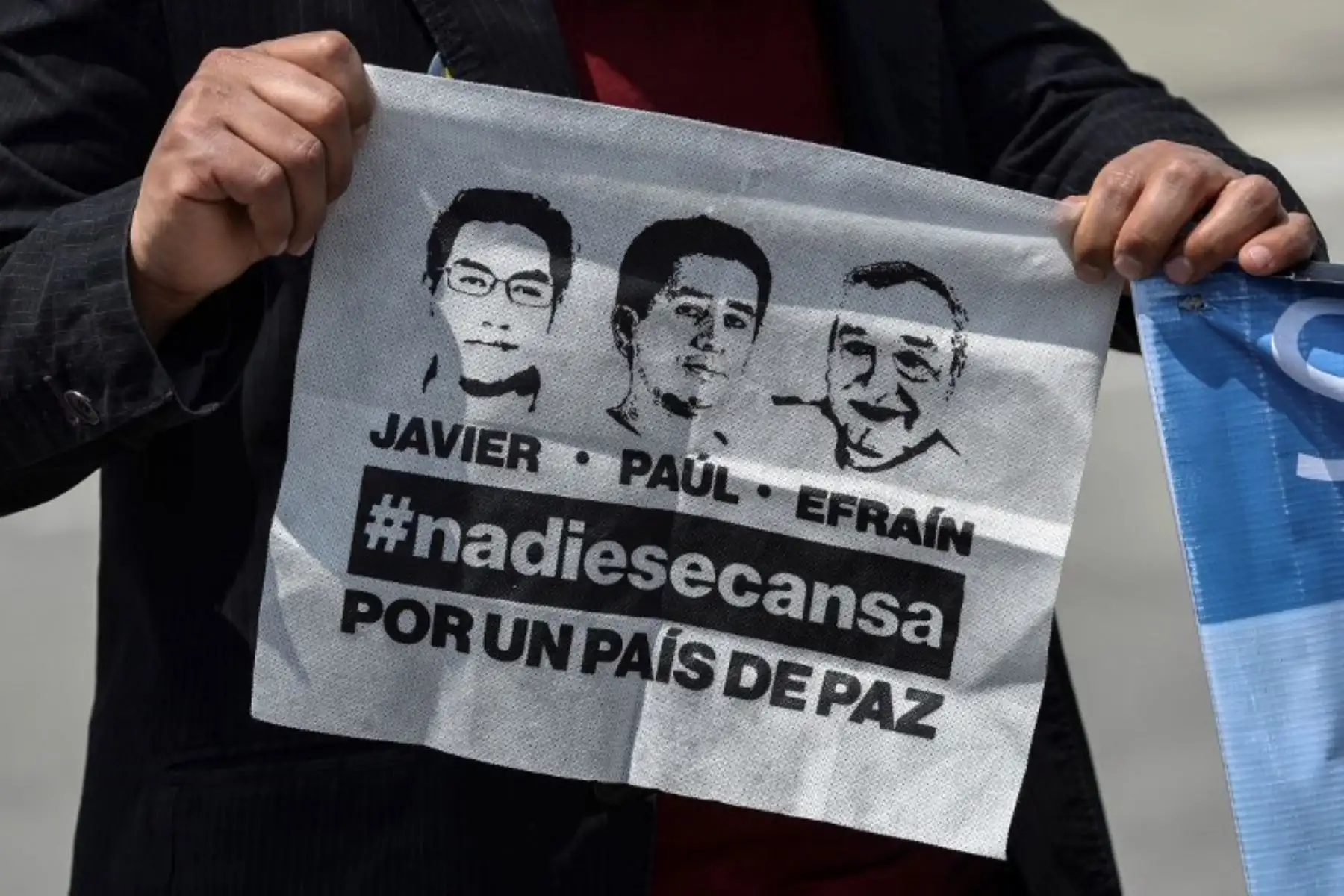 Un hombre sostiene un pañuelo que representa al periodista ecuatoriano de El Comercio Javier Ortegaphotographer Paul Rivas y al conductor Efraín Segarra cuando sus familiares llegan al aeropuerto Alfonso Bonilla Aragón en Palmira, Colombia.Foto:AFP