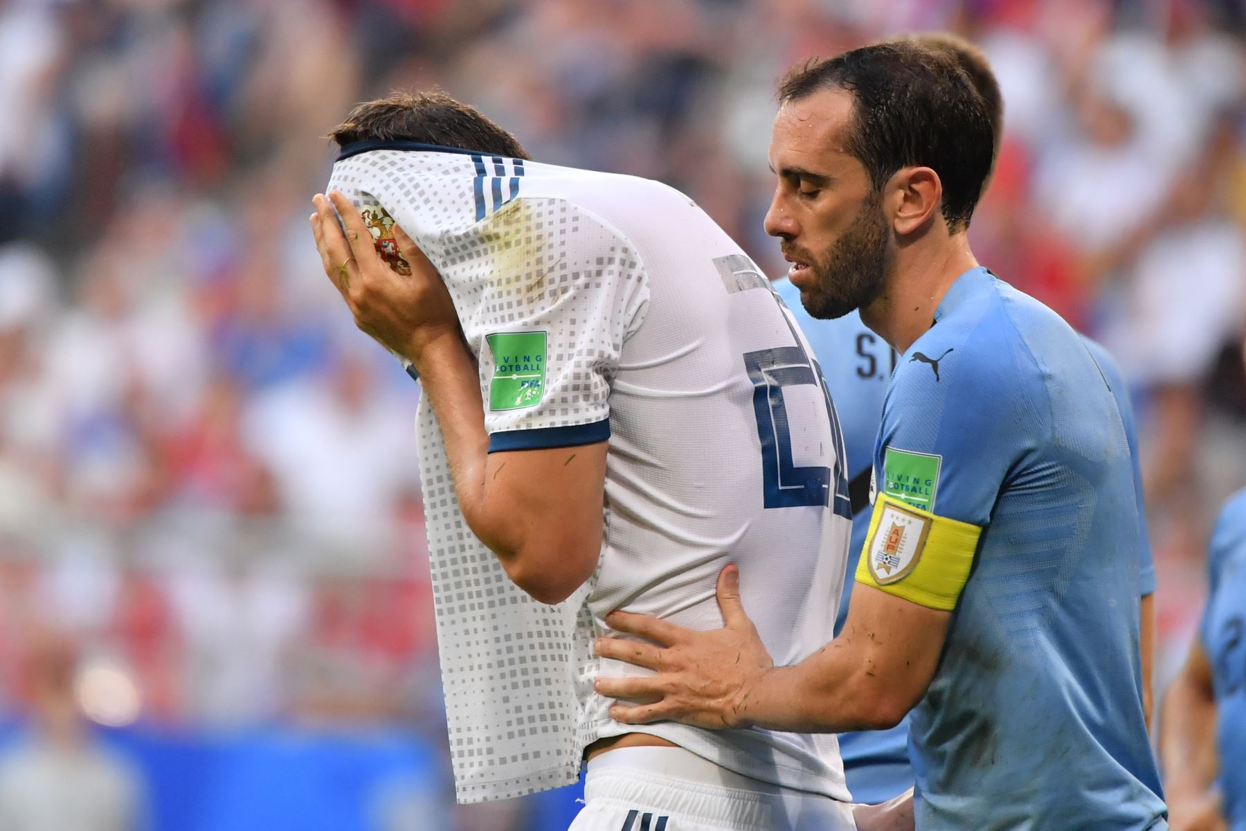 El delantero ruso Artem Dzyuba se cubre la cara después de caer tras una falta del defensor uruguayo Diego Godin (R) durante el partido de fútbol del Grupo A de la Copa Mundial Rusia 2018 entre Uruguay y Rusia en el Samara Arena de Samara el 25 de junio de 2018. / AFP