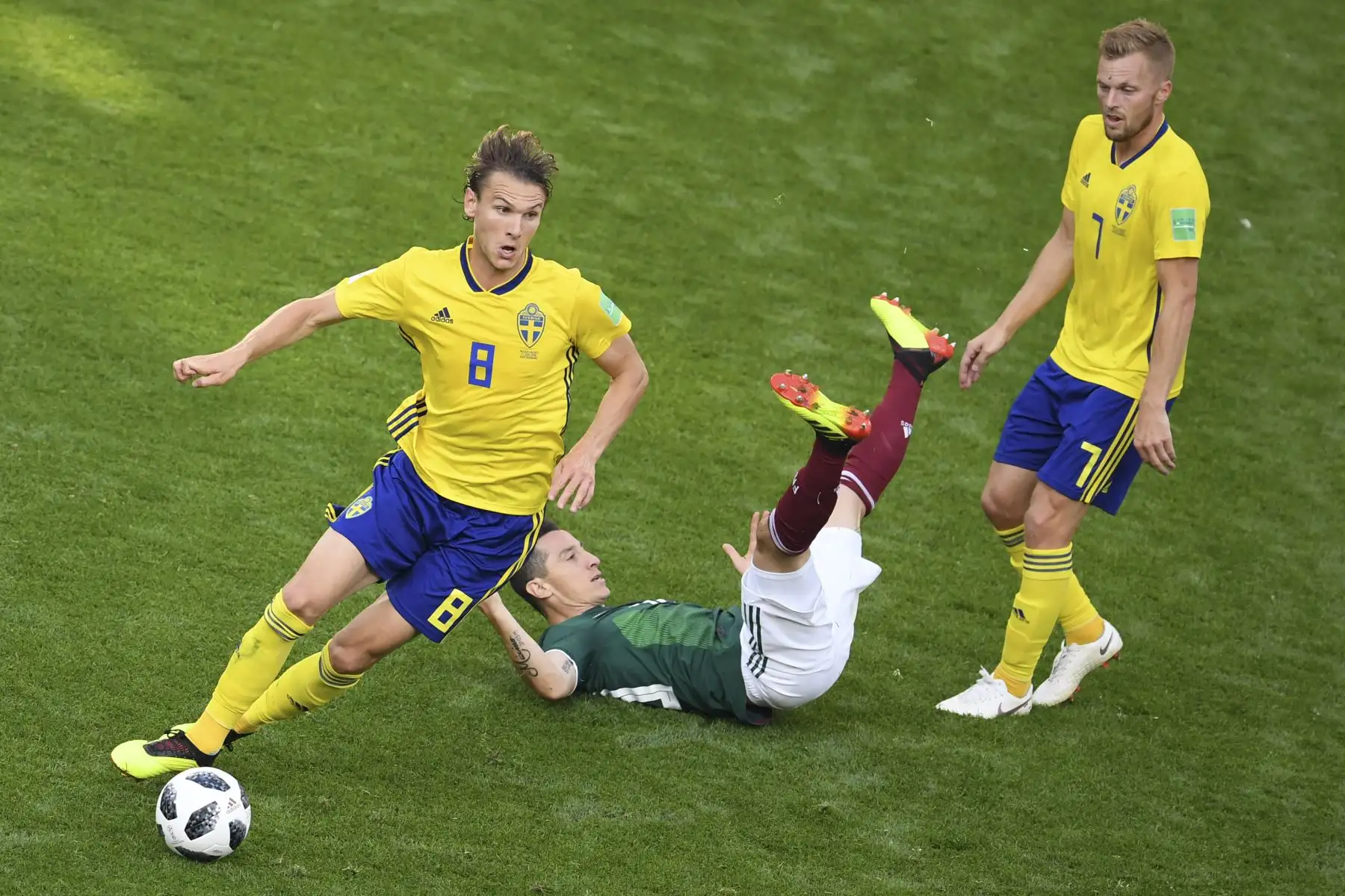 El centrocampista sueco Albin Ekdal enfrenta al centrocampista mexicano Héctor Herrera, que cae sobre el césped, durante el partido de fútbol del grupo F de la Copa Mundial de Rusia 2018 entre México y Suecia en el Ekaterinburg Arena, el 27 de junio del 2018. Foto: AFP.