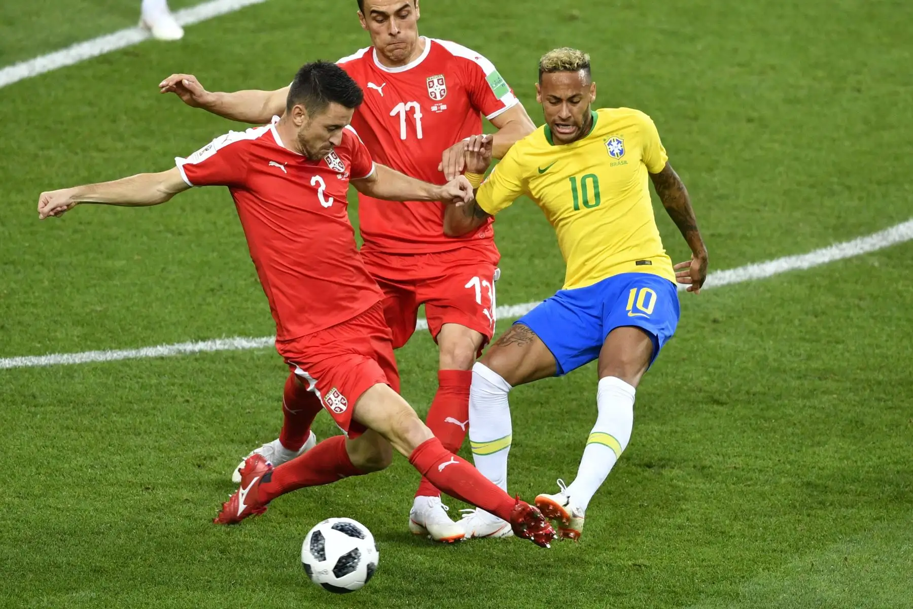 El delantero brasileño Neymar (R) reta al delantero serbio Filip Kostic (C) y al defensor serbio Antonio Rukavina (L) durante el partido de fútbol del Grupo E de la Copa Mundial Rusia 2018 entre Serbia y Brasil en el Estadio Spartak de Moscú el 27 de junio de 2018. / AFP