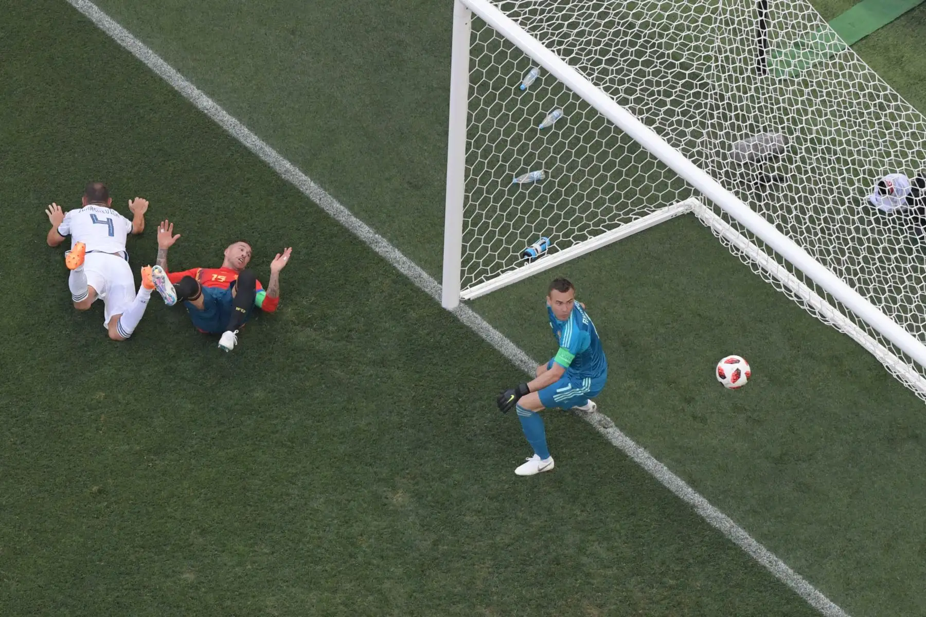 El defensa de España Sergio Ramos (C) cae cuando el defensor ruso Sergey Ignashevich (L) marca un gol en la ronda de octavos de final de la Copa Mundial Rusia 2018 entre España y Rusia en el Estadio Luzhniki en Moscú el 1 de julio de 2018. / AFP