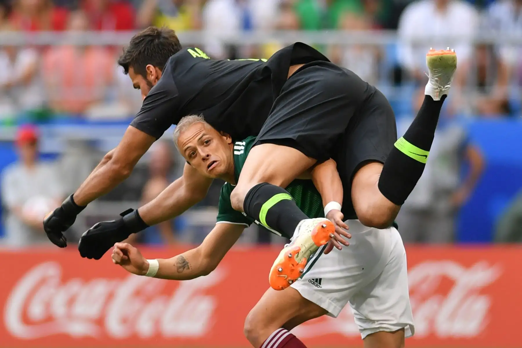 El portero brasileño Alisson salta sobre el delantero mexicano Javier Hernández mientras compiten por el balón durante la ronda de rondas 16 de la Copa Mundial Rusia 2018 entre Brasil y México en el Samara Arena en Samara el 2 de julio de 2018.
 / AFP