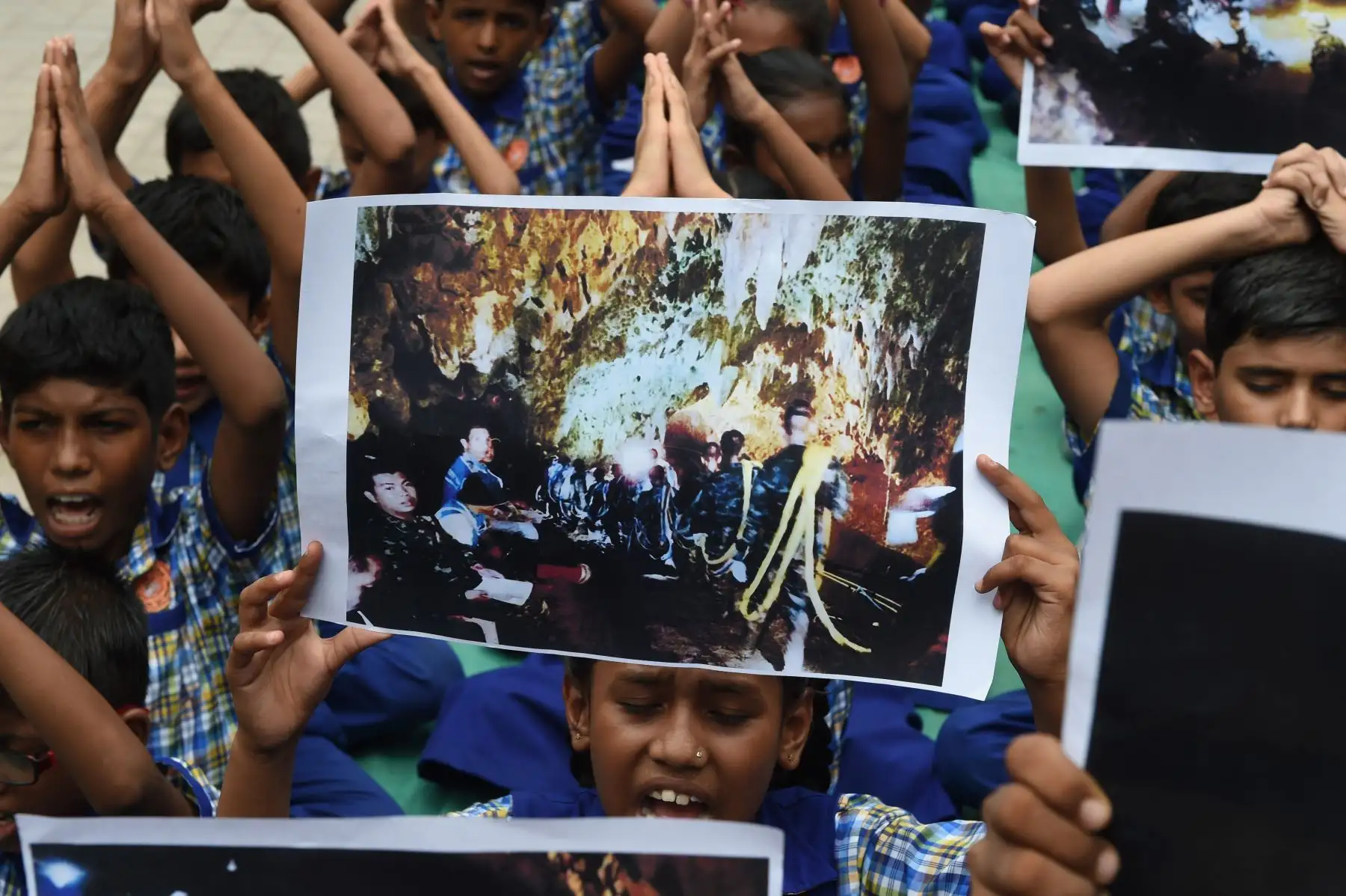 Los escolares indios sostienen carteles e imágenes durante un evento de oración para el rescate seguro de los jóvenes jugadores de fútbol y su entrenador atrapado en una cueva en Tailandia, en Ahmedabad el 9 de julio de 2018. AFP