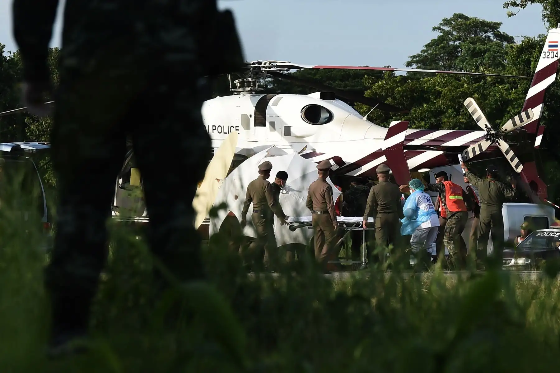 Los trabajadores de rescate llevan una camilla cerca de un helicóptero de la policía en un aeropuerto militar en Chiang Rai el 9 de julio de 2018, mientras continúan las operaciones de rescate para los que aún están atrapados dentro de la cueva en Khun Nam Nang Non Forest Park en el distrito de Mae Sai. AFP