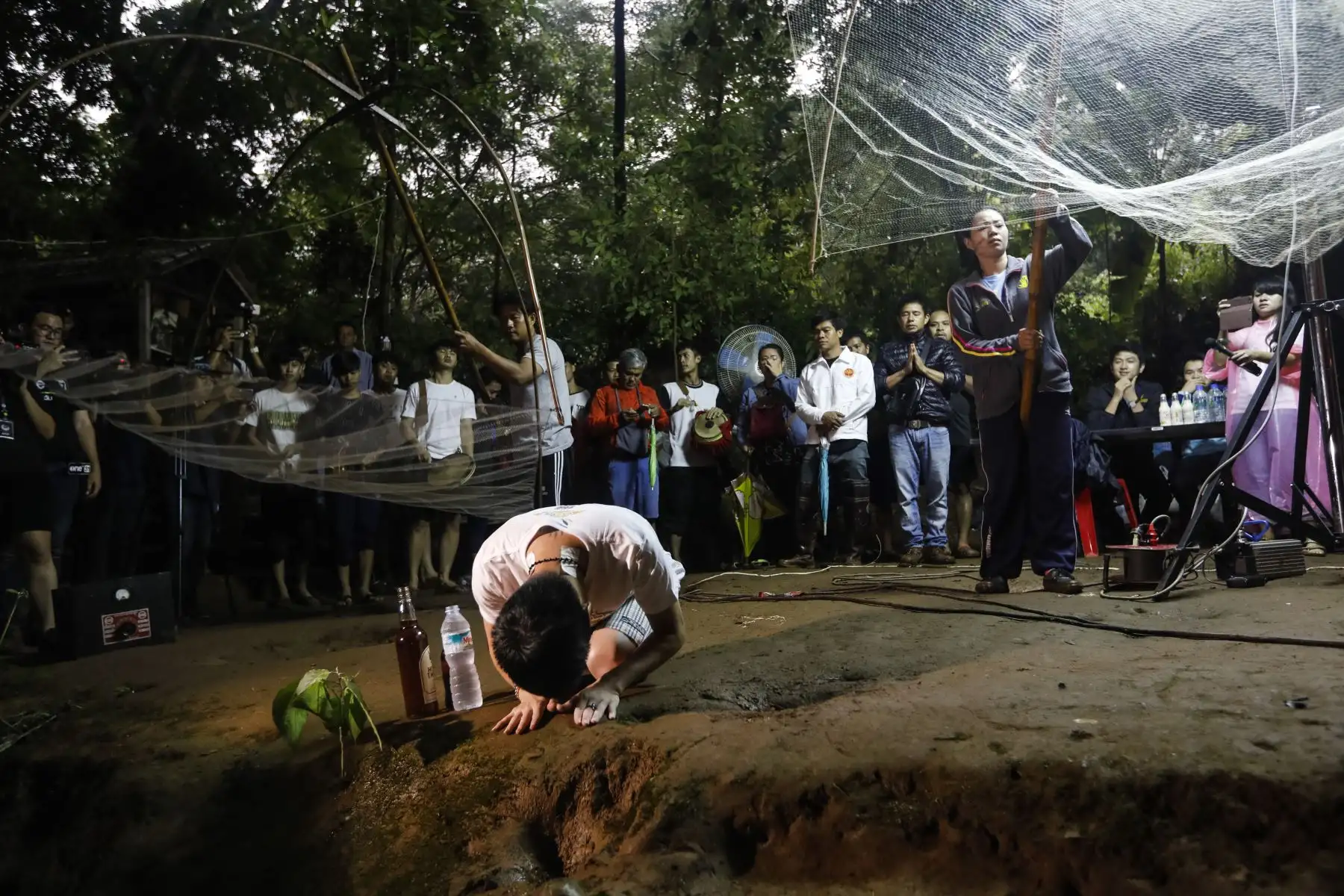 Familiares y parientes rezan en la entrada de la cueva Tham Luang mientras el personal de rescate realiza operaciones para encontrar a los miembros del equipo de fútbol infantil desaparecidos junto con su entrenador en la cueva del Parque No forestal Khun Nam Nang en la provincia de Chiang Rai.AFP