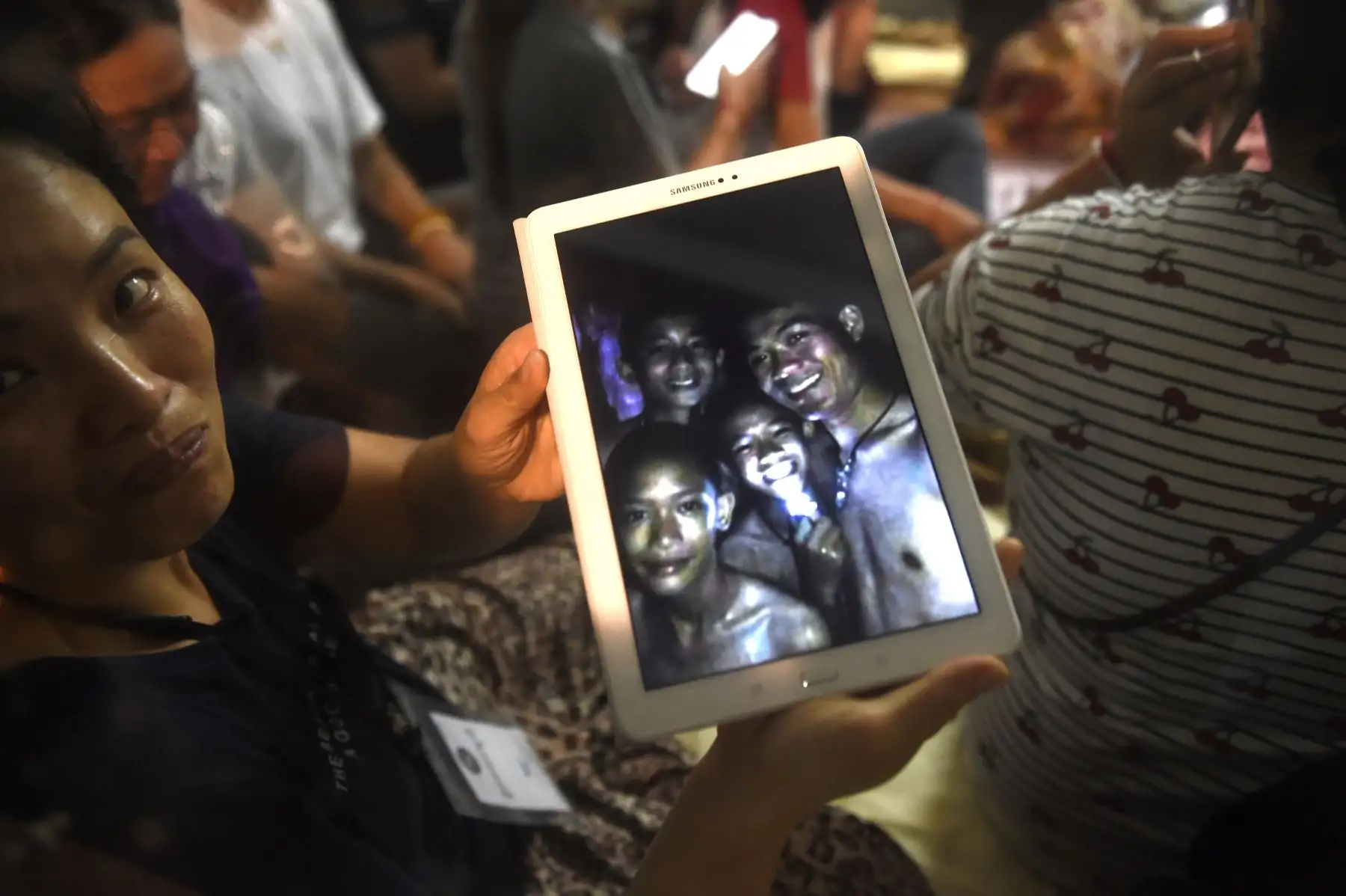 Thanaporn Promthep, madre de uno de los 12 niños desaparecidos, muestra una imagen que se cree que fue tomada en 2017 de su hijo Duangpetch Promthep, apodado "Dom" (en la foto 2da R-con luz) y su entrenador de fútbol Ekkapol Chantawong (R), después de escuchar las noticias, el grupo fue encontrado, cerca de la cueva de Tham Luang en el Parque Forestal Khun Nam Nang en el distrito de Mae Sai. Foto: AFP