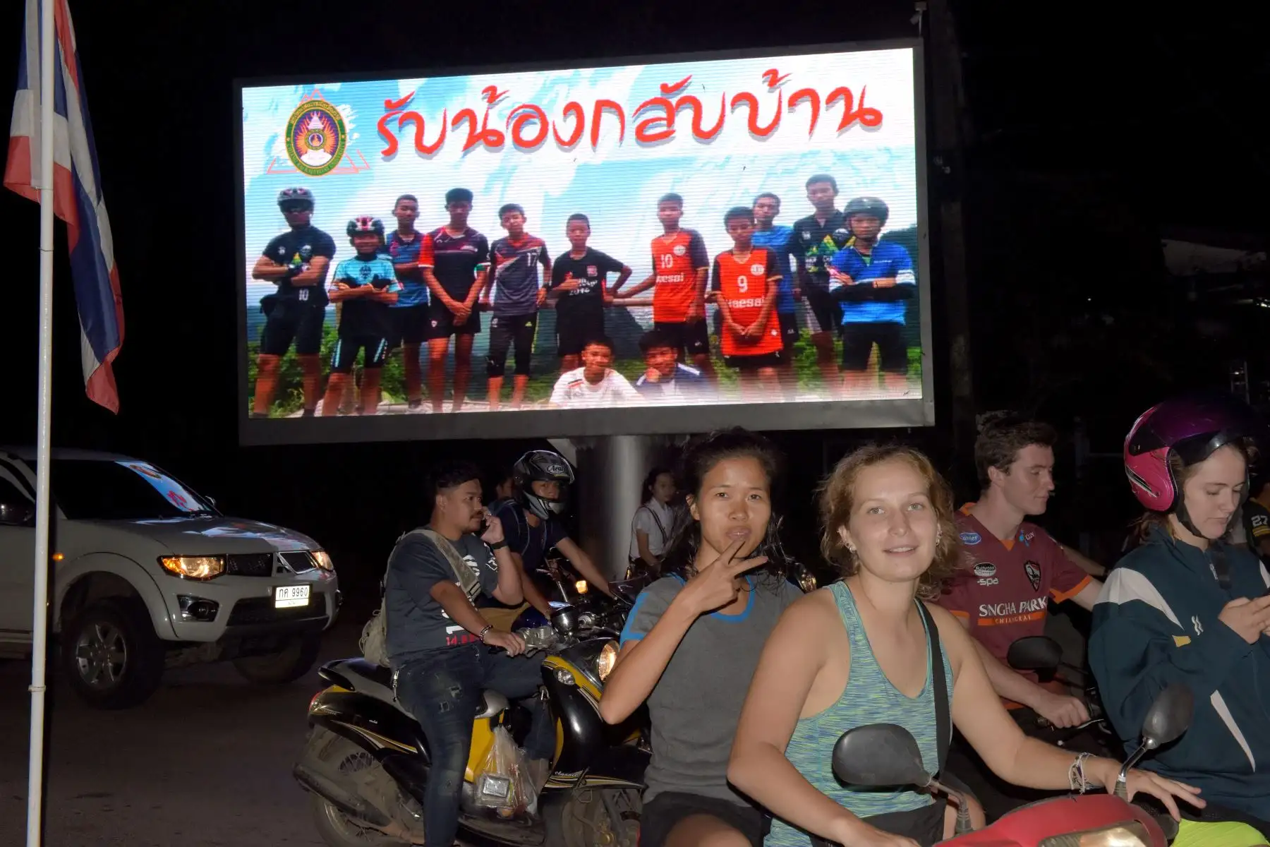 Los automovilistas pasan una cartelera con una fotografía que muestra a miembros del equipo tailandés de fútbol "Wild Boar" y su entrenador con un mensaje "bienvenidos a casa hermanos" exhibidos en Chiang Rai mientras los chicos y su entrenador fueron rescatados en la cueva de Tham Luang en Khun Nam Nang Non Forest Park en el distrito de Mae Sai el 10 de julio de 2018. AFP