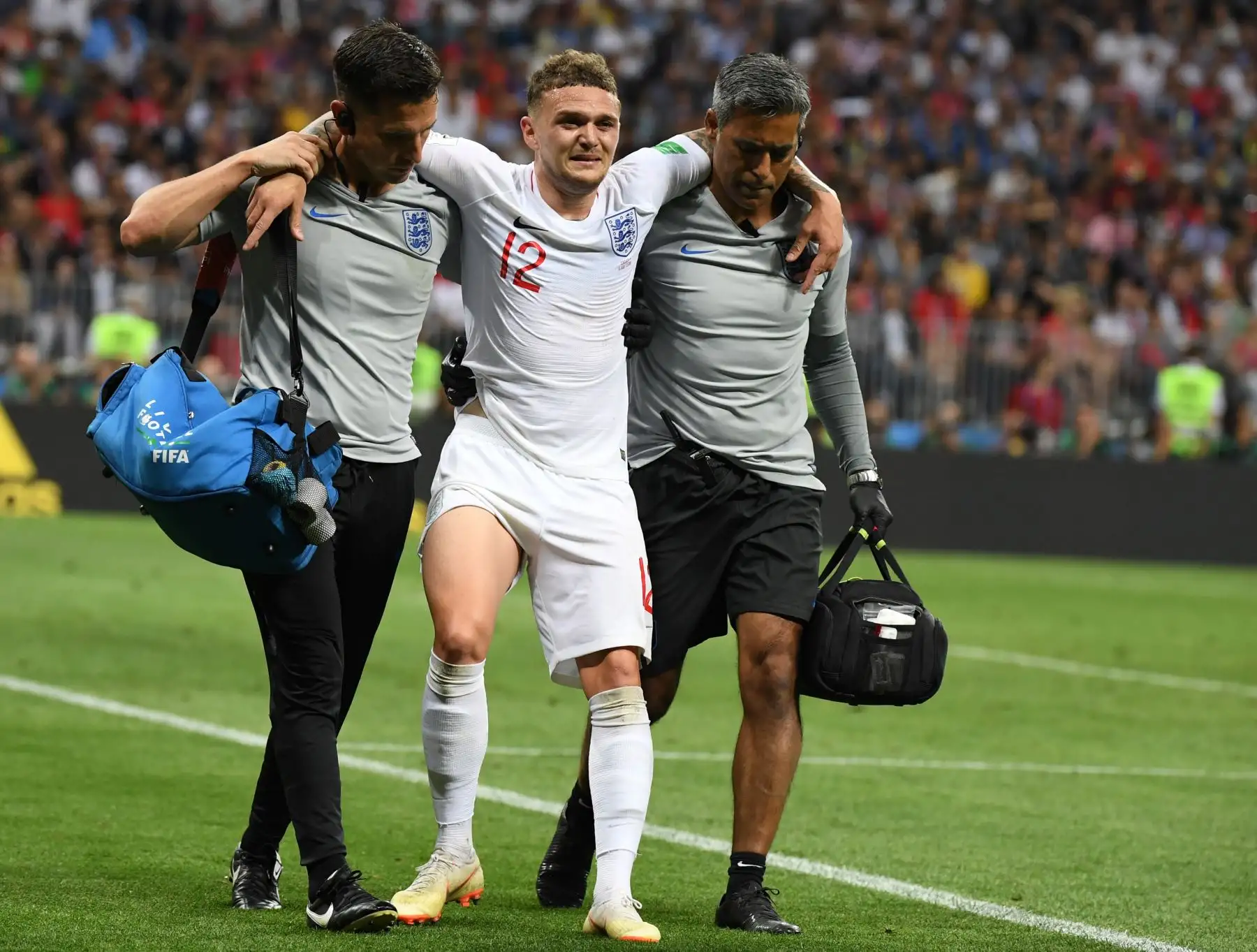 El defensor de Inglaterra Kieran Trippier (C) reacciona mientras es escoltado fuera del terreno de juego por un equipo médico durante el partido de semifinales de la Copa Mundial Rusia 2018 entre Croacia e Inglaterra en el Estadio Luzhniki en Moscú el 11 de julio de 2018. / AFP