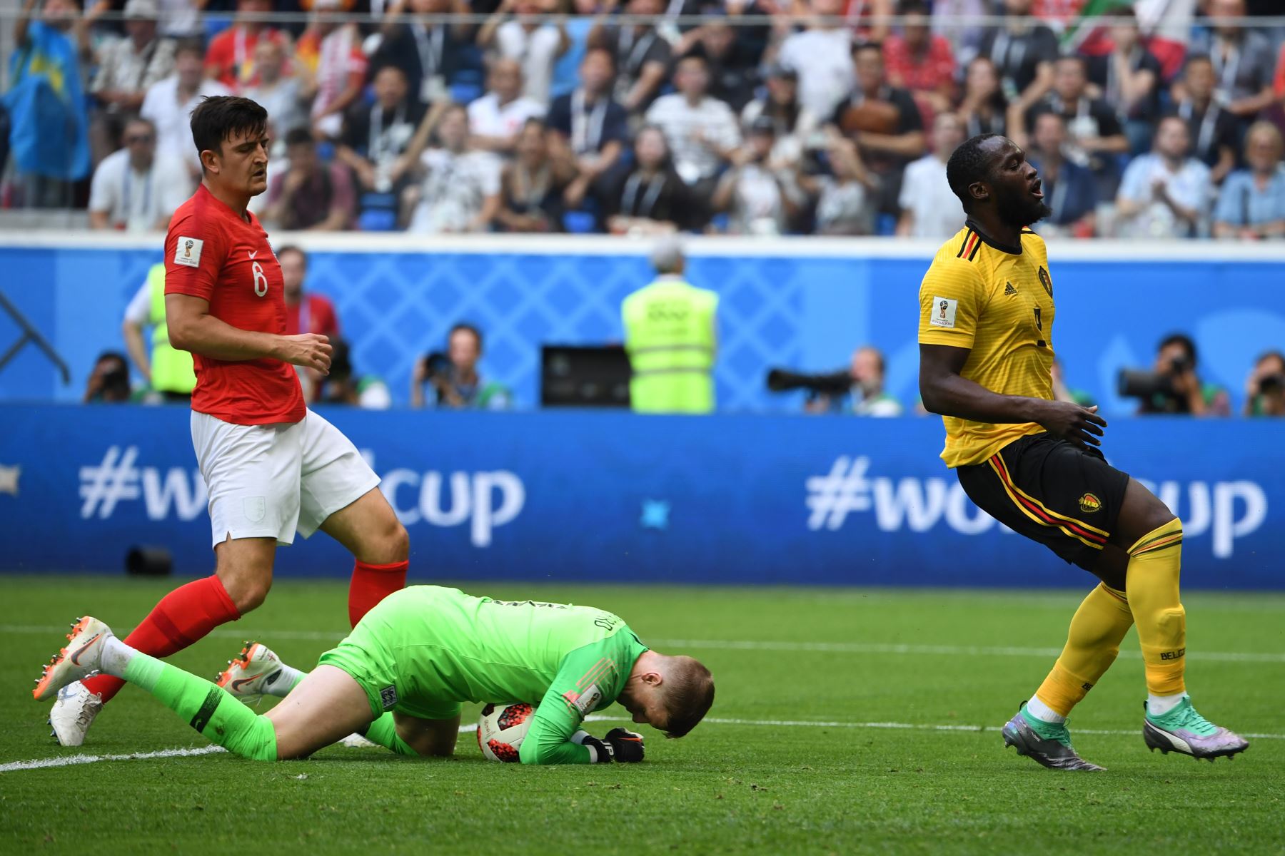 El portero de Inglaterra Jordan Pickford (C) hace un salvamento cuando el alero belga Romelu Lukaku (R) y el defensa de Inglaterra Harry Maguire reaccionan durante el partido por la Copa Mundial 2018 Rusia por el tercer partido de fútbol entre Bélgica e Inglaterra en el estadio de San Petersburgo en San Petersburgo el 14 de julio de 2018. / AFP