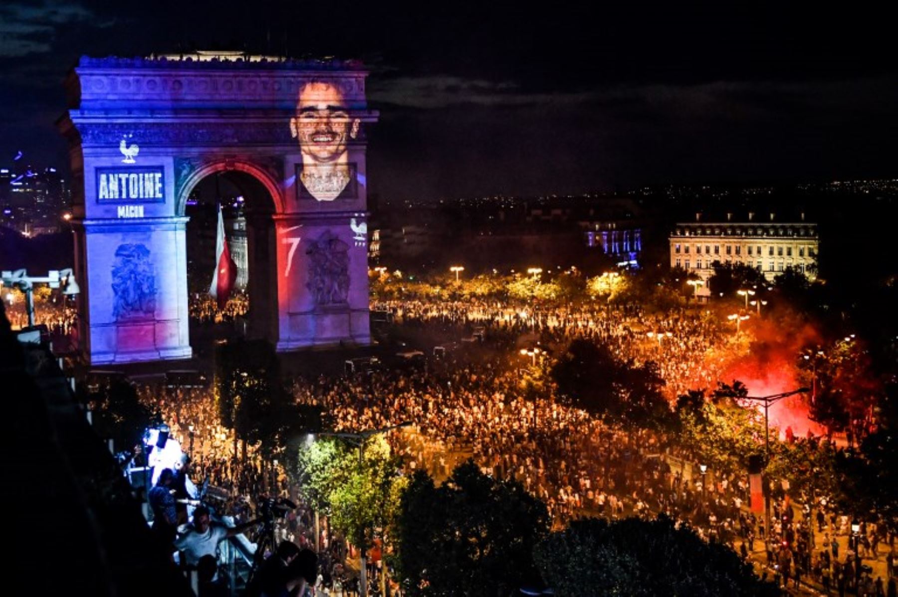 Retrato del delantero francés Antoine Griezmann proyectado en el Arco del Triunfo de París, mientras la gente  celebra la victoria de Francia como campeón de la Copa Mundial Rusia 2018.Foto:AFP