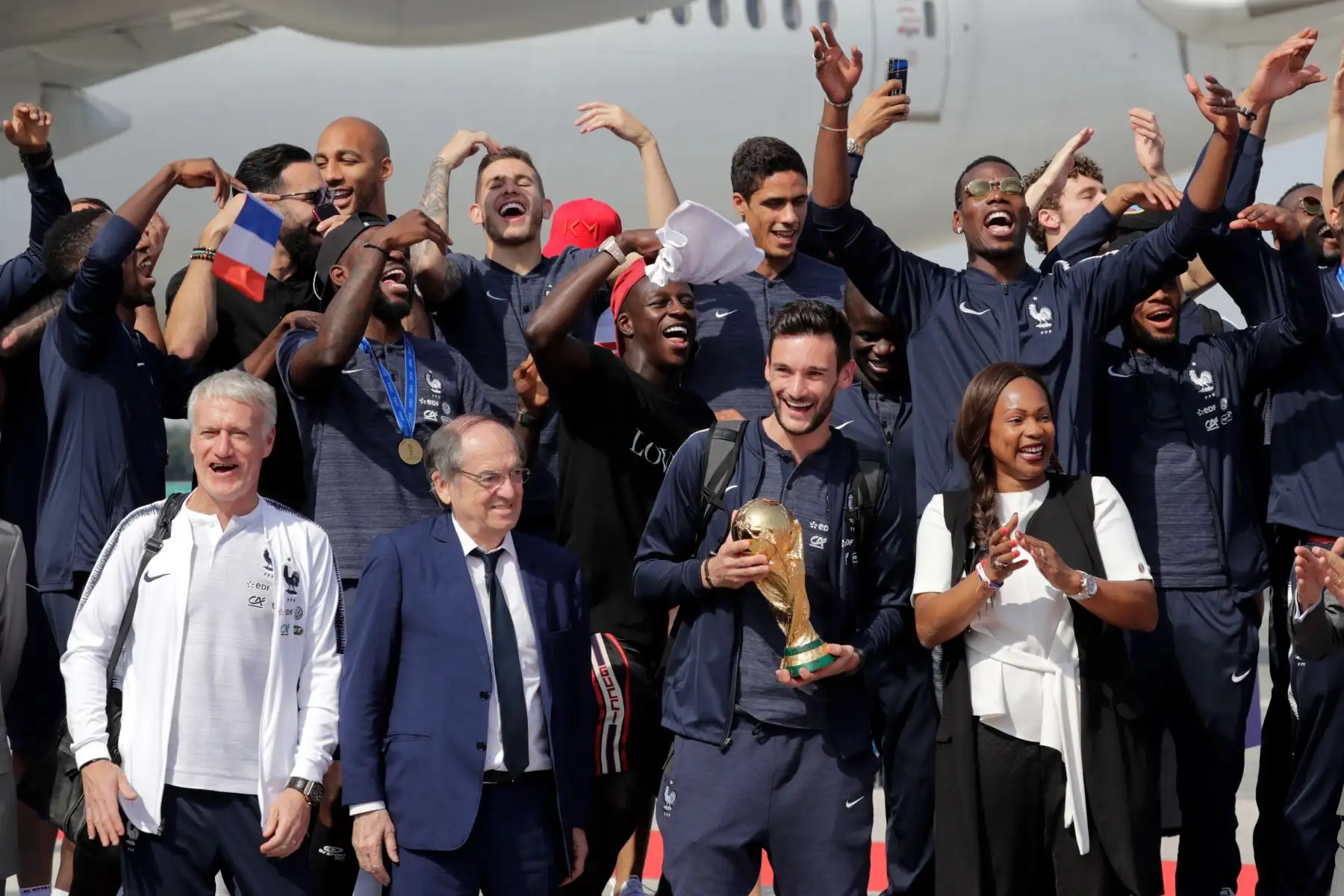 El portero francés Hugo Lloris ostenta el trofeo mientras celebra con sus compañeros y presidente de la Federación Francesa de Fútbol Noel Le Graet, la ministra de deportes francesa Laura Flessel y el seleccionador francés Didier Deschamps  a su llegada al Aeropuerto Roissy-Charles de Gaulle a las afueras de París. AFP