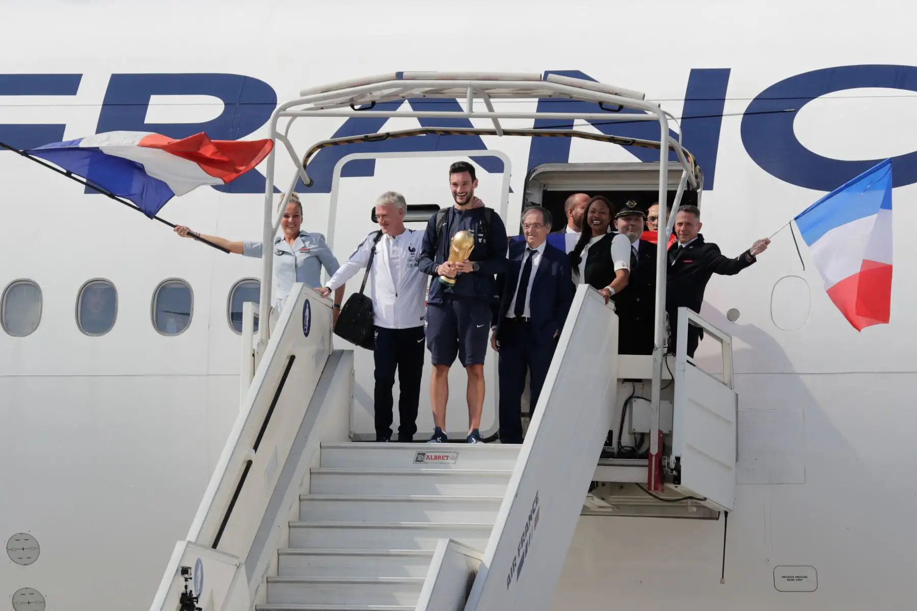 El arquero de Francia, Hugo Lloris, sostiene el trofeo mientras baja del avión junto al entrenador de Francia Didier Deschamps , el presidente de la Federación Francesa de Fútbol Noel Le Graet  y la ministra de Deportes de Francia Laura Flessel  en el aeropuerto Roissy-Charles de Gaulle a las afueras de París. AFP