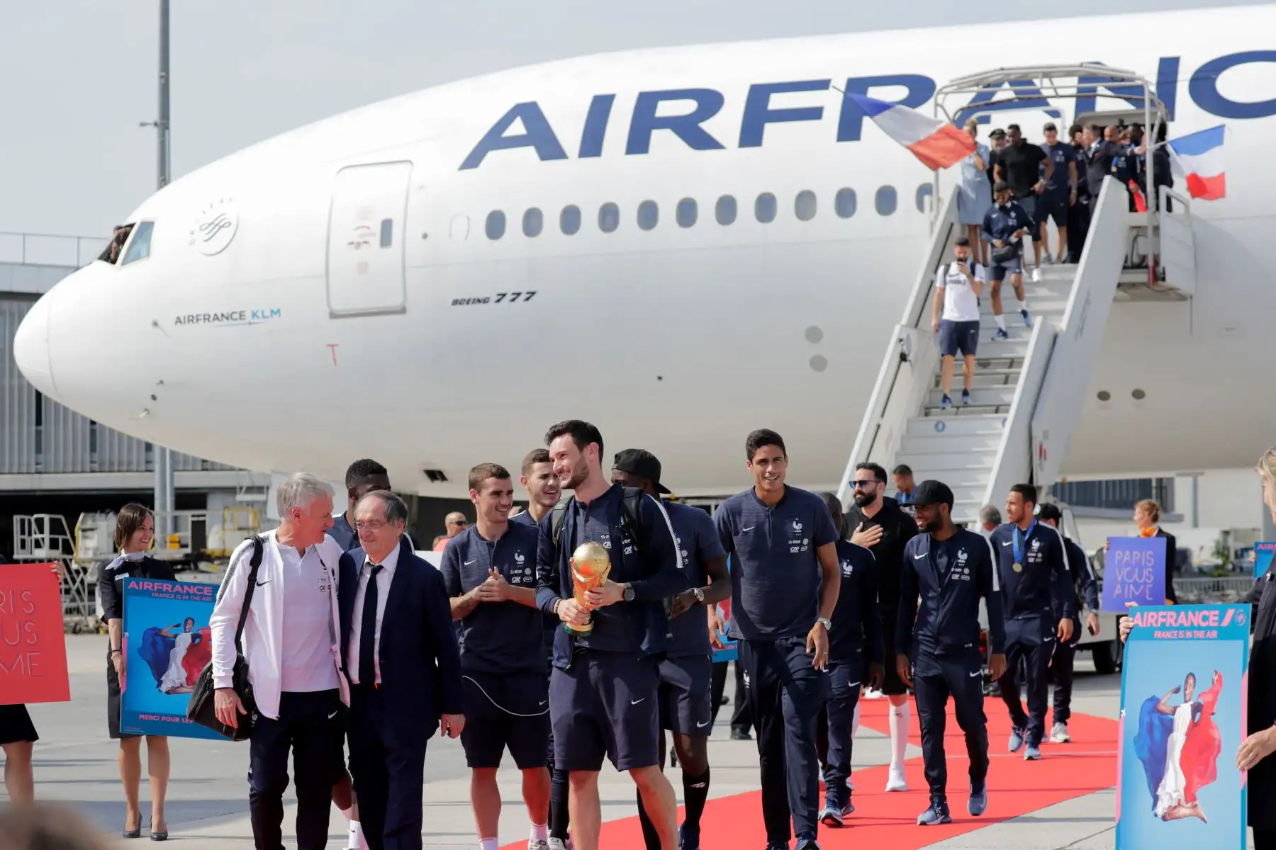 El portero francés Hugo Lloris, flanqueado por el entrenador francés Didier Deschamps, el presidente de la Federación Francesa de Fútbol Noel Le Graet, el delantero francés Antoine Griezmann  y el defensor francés Raphael Varane, trofeo mientras celebra con sus compañeros de equipo mientras desembarcan del avión a su llegada al aeropuerto Roissy-Charles de Gaulle en las afueras de París. AFP
