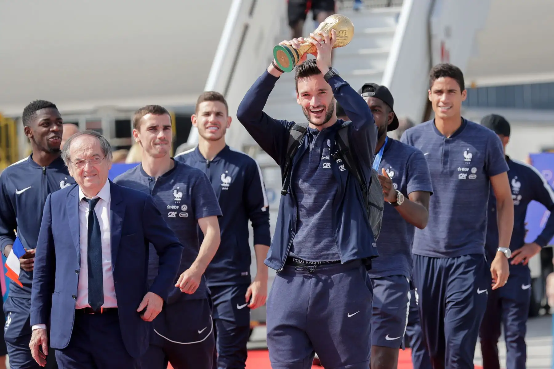 El portero de Francia Hugo Lloris, flanqueado por el presidente de la Federación Francesa de Fútbol Noel Le Graet  y el delantero francés Antoine Griezmann, ostenta el trofeo mientras celebra su desembarco del avión a su llegada al aeropuerto Roissy-Charles de Gaulle tras ganar  la Copa Mundial Rusia 2018. AFP