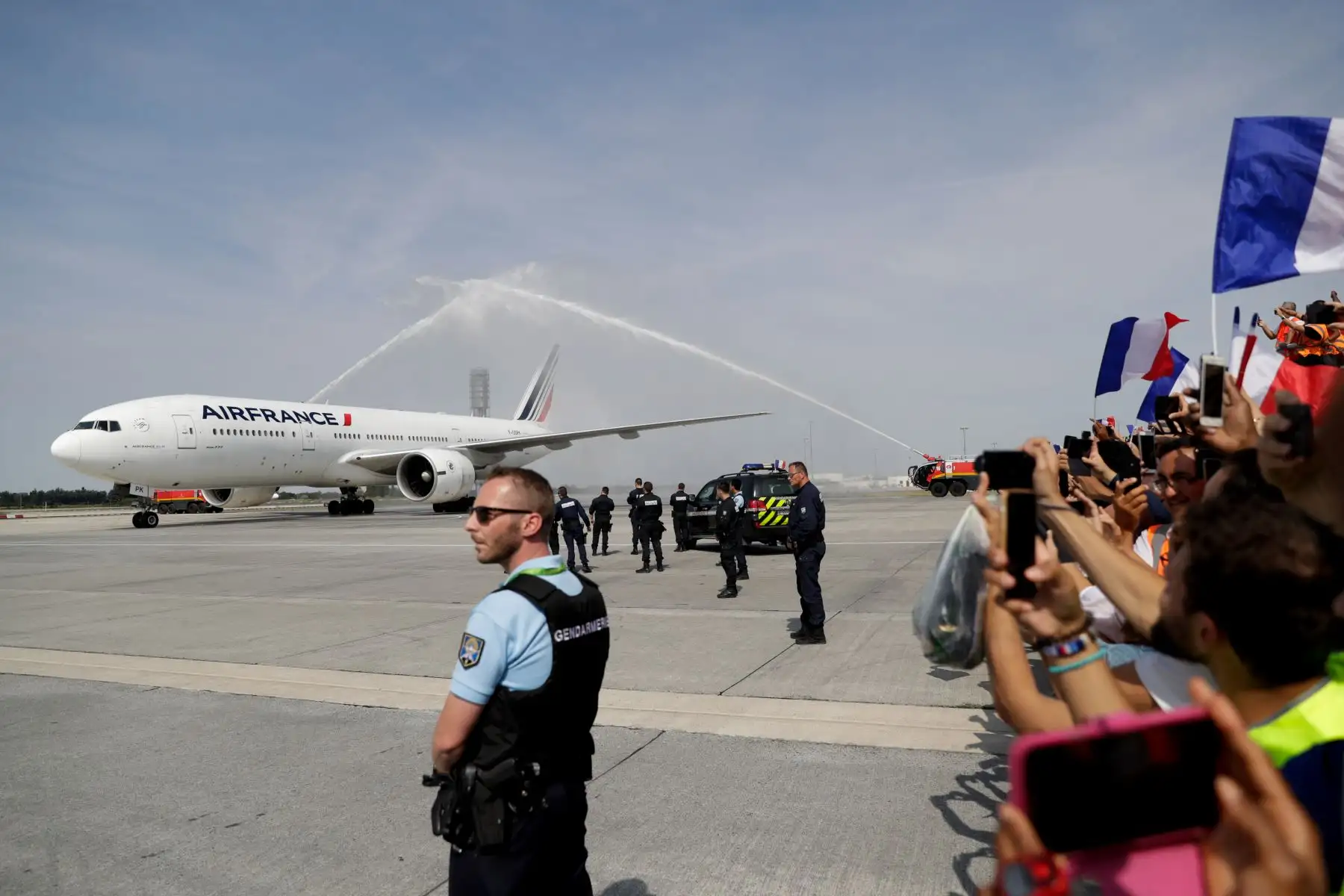 Los fanáticos de Francia ondean banderas nacionales francesas al aterrizar el avión que transporta al equipo nacional de fútbol de Francia en el aeropuerto Roissy-Charles de Gaulle. AFP