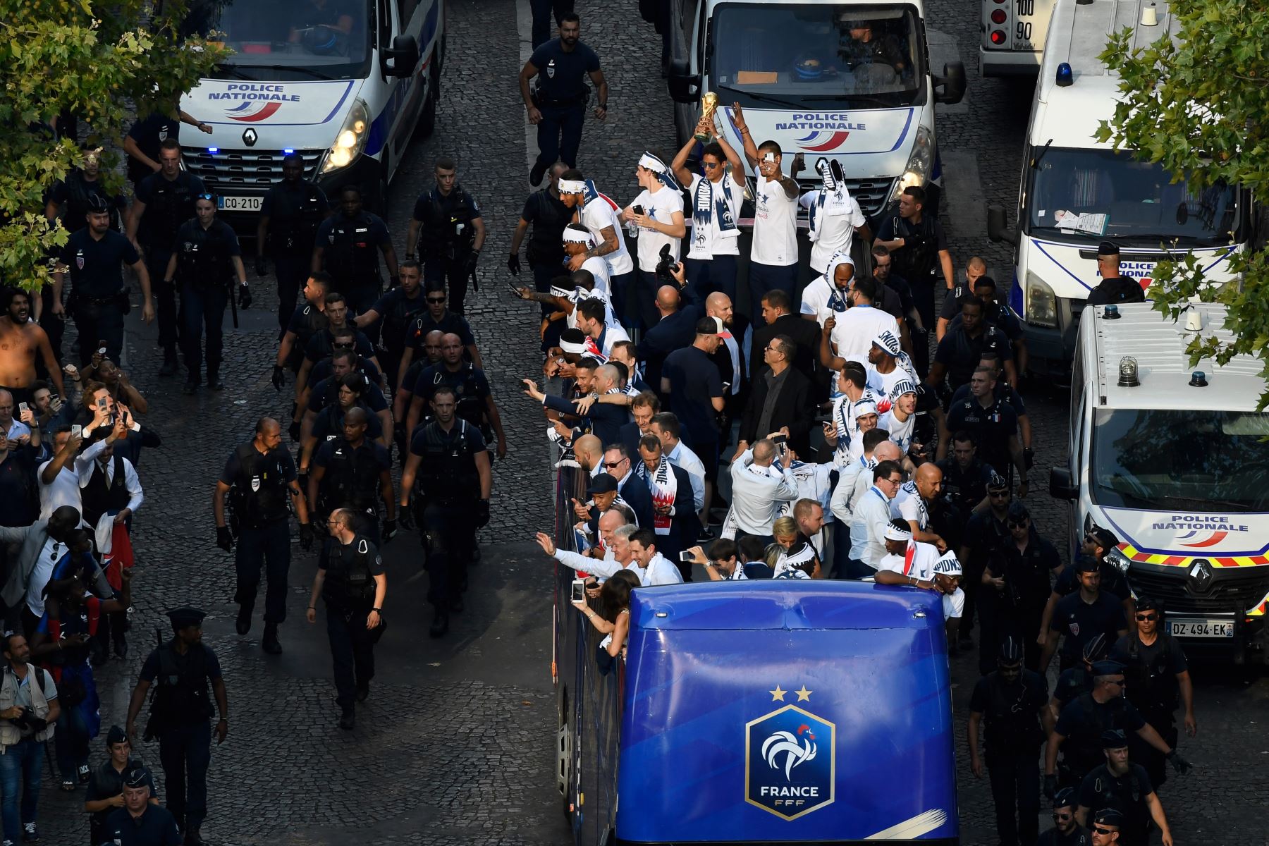 El defensor de Francia Raphael Varane  ostenta el trofeo mientras celebra con sus compañeros de equipo en el techo de un autobús cuando llegan a la avenida de los Campos Elíseos en París. AFP