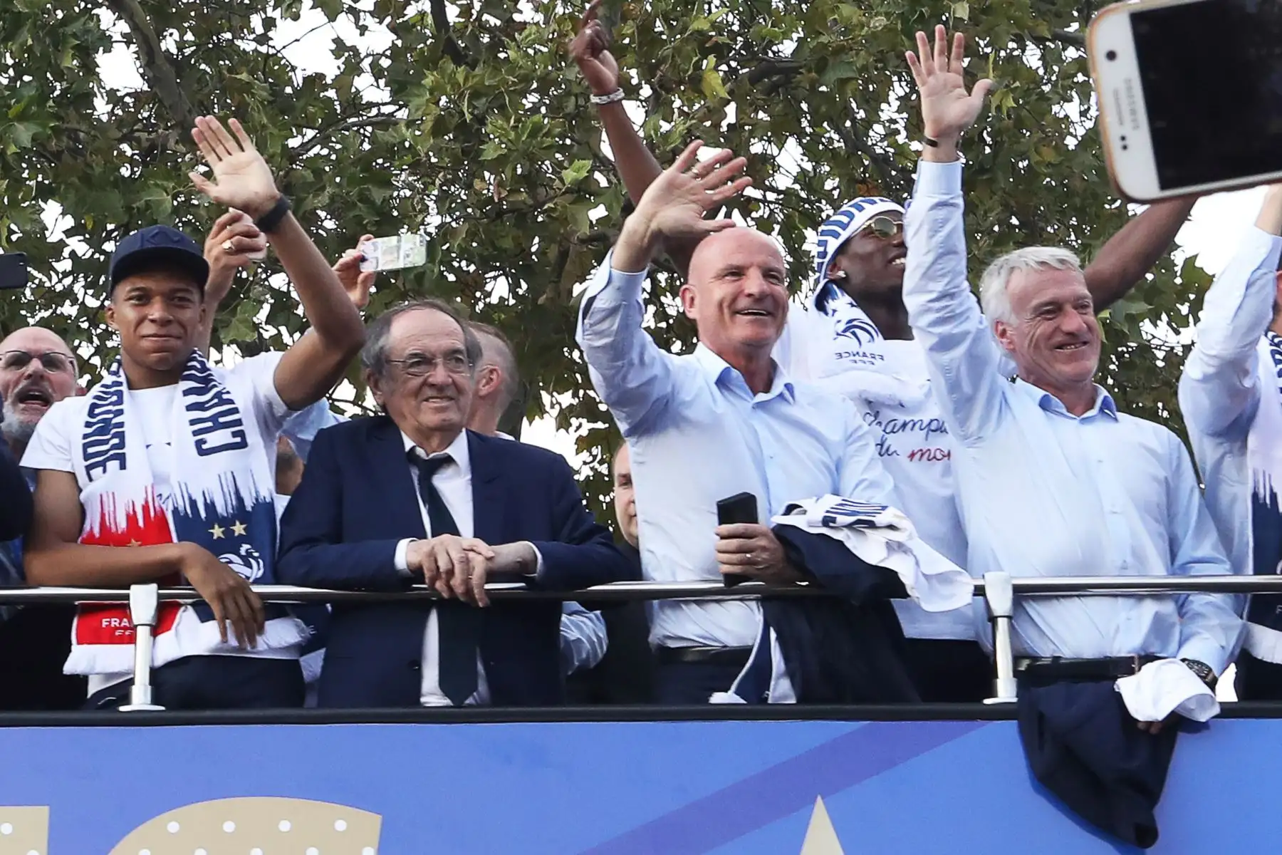 El delantero francés Kylian Mbappe, el presidente de la Federación Francesa de Fútbol Noel Le Graet, el asistente técnico francés Guy Stephan  y el entrenador francés Didier Deschamps celebran con sus compañeros y miembros del personal en el techo de un autobús mientras desfilan por la avenida Champs-Elysee en París. AFP