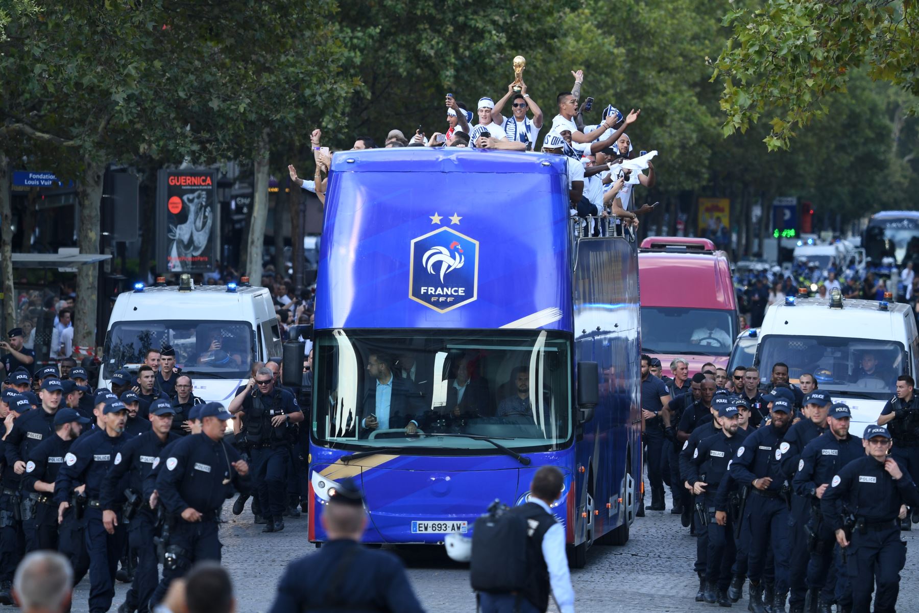 El defensor de Francia Raphael Varane  sostiene el trofeo mientras celebra con sus compañeros en el techo de un autobús mientras desfila por la avenida Champs-Elysee en París después de ganar el partido de fútbol final de la Copa Mundial Rusia 2018. AFP