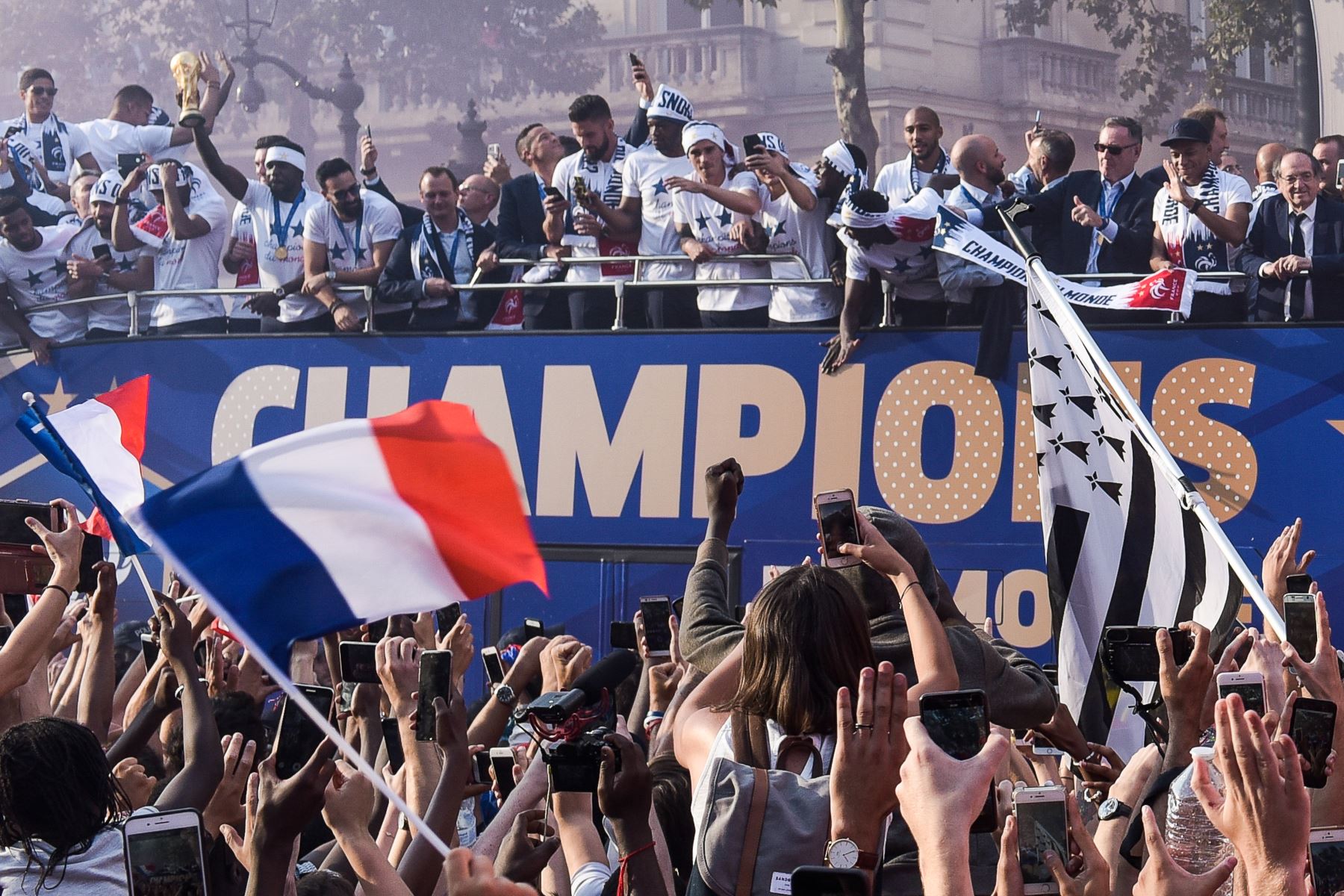 El defensa de Francia Samuel Umtiti  sostiene el trofeo mientras celebra con sus compañeros en el techo de un autobús mientras desfila por la avenida Champs-Elysee en París,  después de ganar el partido de fútbol final de la Copa Mundial Rusia 2018. AFP