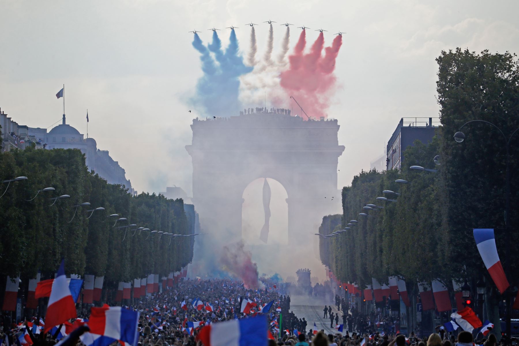 Los jets Patrouille de France, trailing humo en los colores de la bandera nacional, sobrevolar la avenida Champs Elysee y el Arco del Triunfo como partidarios de la bienvenida a los jugadores de la selección francesa de fútbol después de que ganaron la Copa del Mundo Rusia 2018 partido final de fútbol en Paris. AFP
