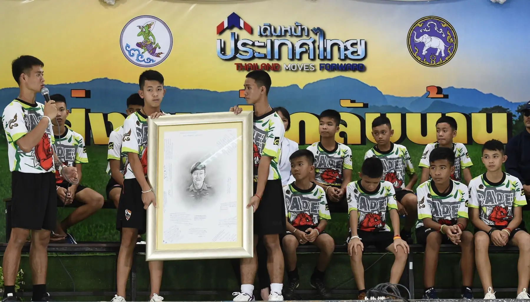El entrenador de fútbol tailandés Ekkapol Chantawong (L) junto con 12 niños rinden homenaje durante una conferencia de prensa en Chiang Rai el 18 de julio de 2018 tras su alta del hospital al voluntario y ex buzo de SEAL de la Marina Saman Kunan que murió durante la operación de rescate.
Los jóvenes futbolistas y su entrenador que quedaron atrapados en un complejo de cuevas inundadas trataron de abrirse camino y sobrevivieron en el agua de lluvia durante nueve días antes de ser encontrados y luego rescatad