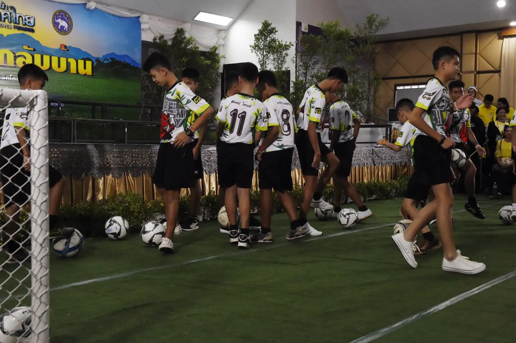 Algunos de los muchachos, rescatados dramáticamente de las profundidades de una cueva, después de estar atrapados por más de una quincena, jugar con balones de fútbol antes de una conferencia de prensa en Chiang Rai el 18 de julio de 2018, tras su alta del hospital .
Los jugadores jóvenes y su entrenador de fútbol parecían sanos cuando se comparaban con los medios por primera vez el 18 de julio. / AFP
