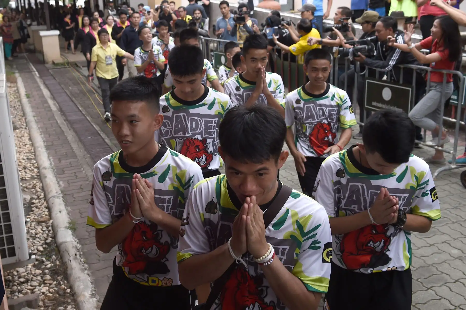 Doce niños y su entrenador de fútbol Ekkapol Chantawong (C), dramáticamente rescatados del interior de una cueva tailandesa después de estar atrapados por más de una quincena, llegan a una conferencia de prensa en Chiang Rai el 18 de julio de 2018, tras su alta del hospital.
Los jóvenes futbolistas y su entrenador parecían sanos cuando comparecieron ante los medios por primera vez el 18 de julio. / AFP