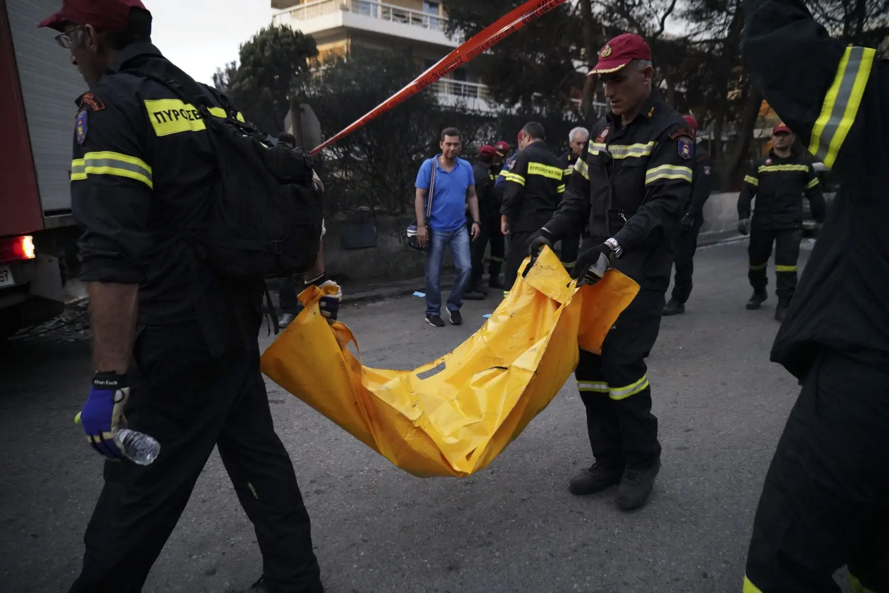 Los bomberos llevan a una persona muerta tras un incendio forestal en la aldea de Mati, cerca de Atenas. AFP