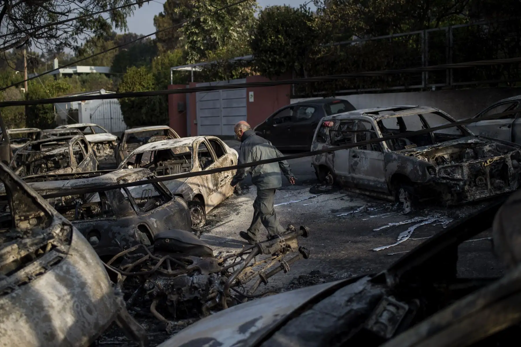 Un hombre camina entre coches quemados después de un incendio forestal en la aldea de Mati, cerca de Atenas. AFP