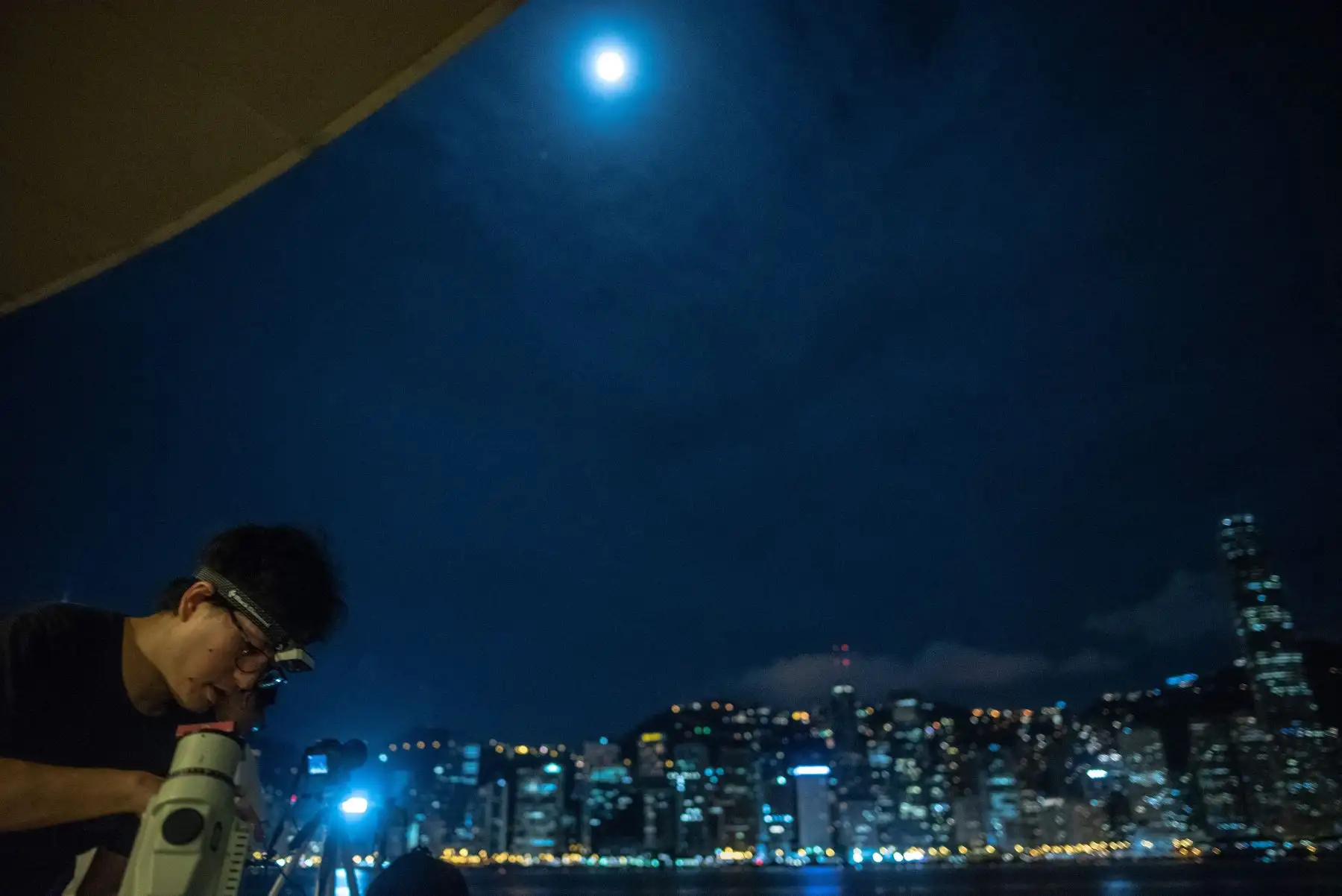 La gente coloca telescopios para observar el eclipse lunar en Hong Kong Foto: AFP