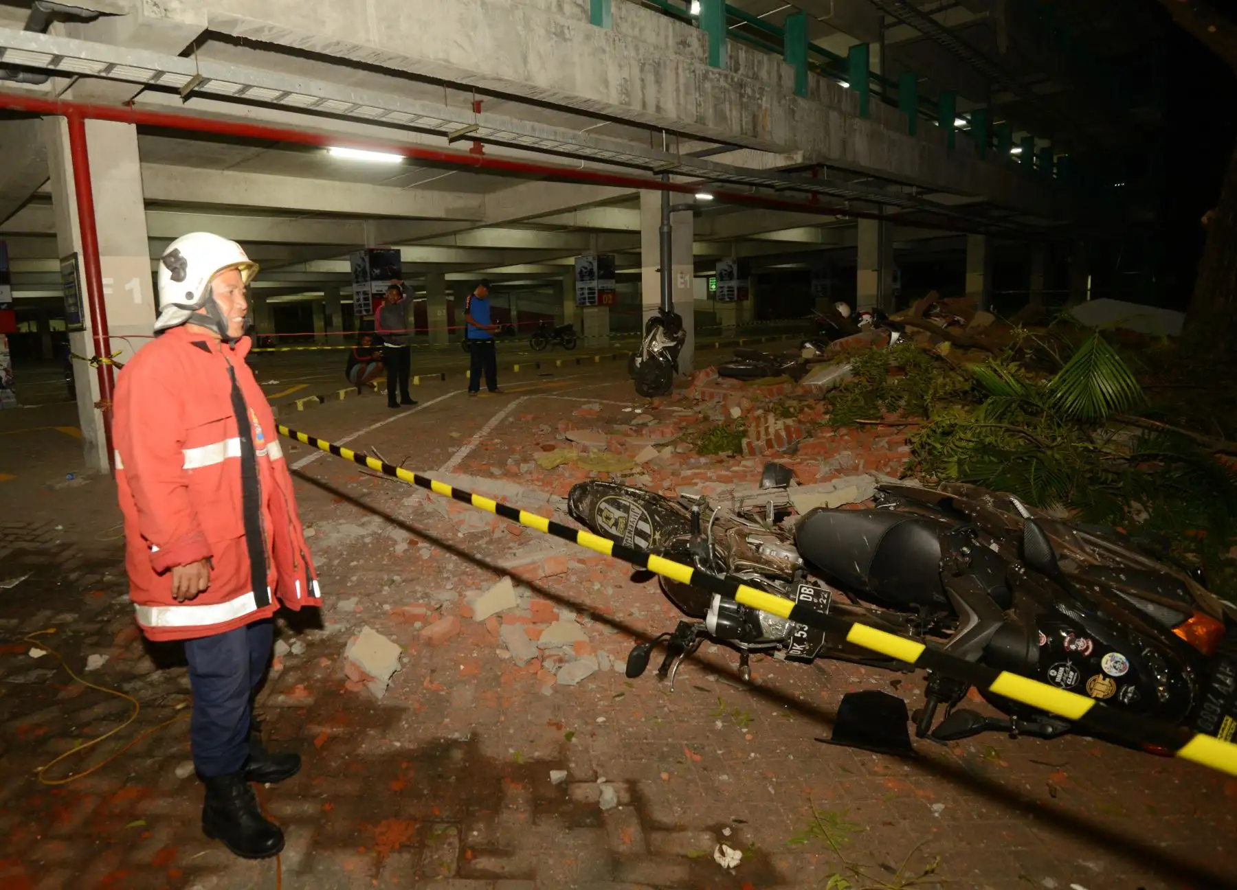 El personal de rescate se encuentra junto a una motocicleta que cayó en un centro comercial en la capital de Bali, Denpasar, el 5 de agosto de 2018, después de que un gran terremoto sacudiera la vecina isla de Lombok. Foto: AFP