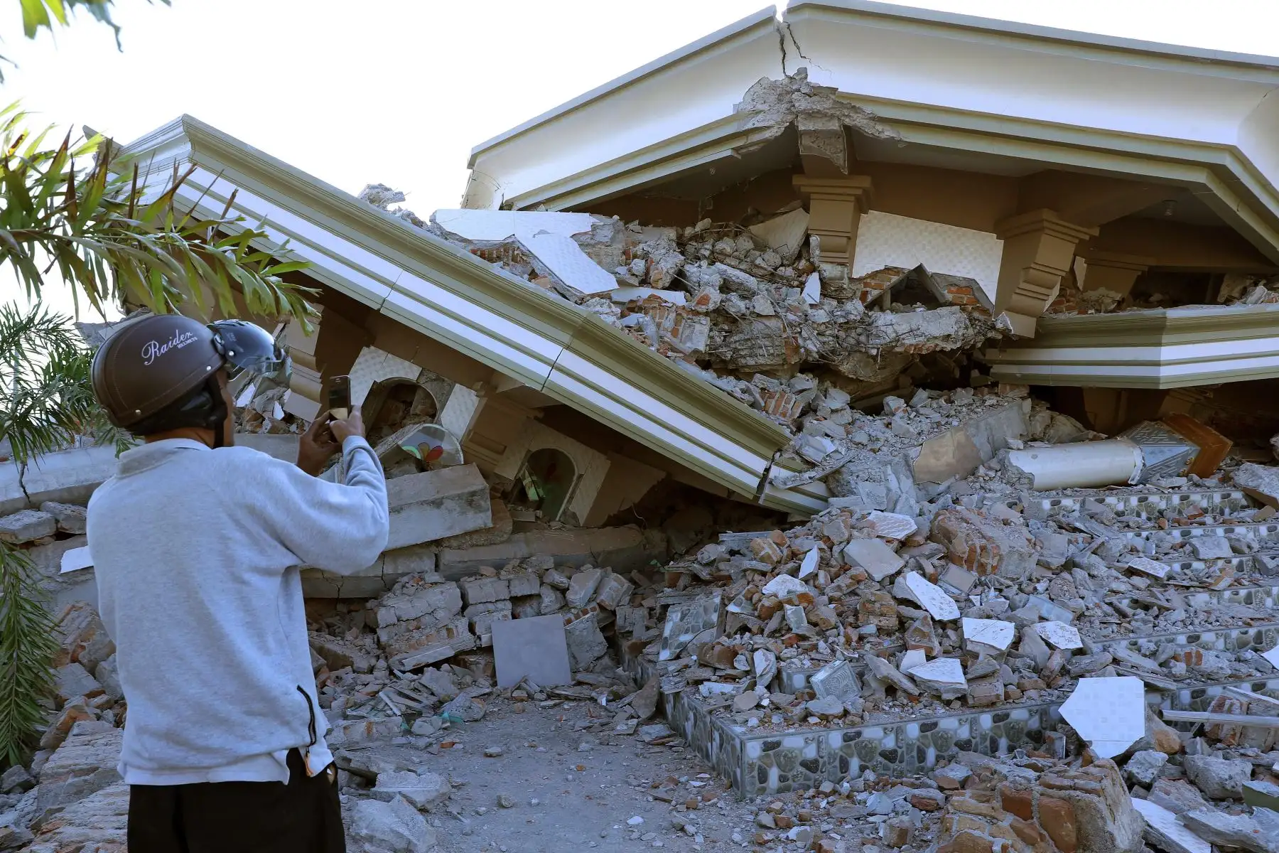 Un hombre toma fotografías de una mezquita derrumbada en Lombok (Indonesia) hoy, 6 de agosto de 2018, tras el terremoto de magnitud 6,9 que sacudió la noche del domingo. Al menos 91 personas han muerto y 209 han resultado heridas en el sismo. EFE