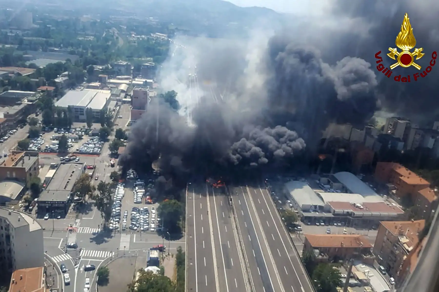 Este folleto, tomado de un helicóptero y lanzado por Vigili del Fuoco, el incendio italiano, el 6 de agosto de 2018, muestra el humo negro que sube en el cielo después de que un camión cisterna explotó en la autopista cerca del aeropuerto, en Bolonia. / AFP