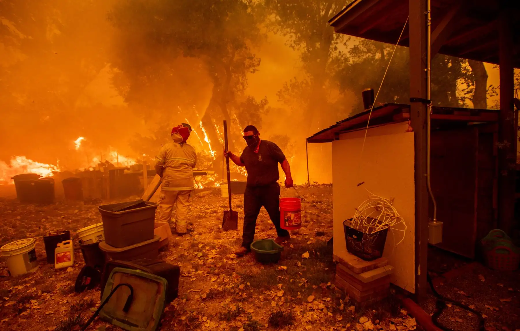 Residentes Lane Lawder lleva un balde de agua mientras lucha para salvar su casa del incendio de Ranch Long New Valley Rd, cerca de Clearlake Oaks, California. AFP