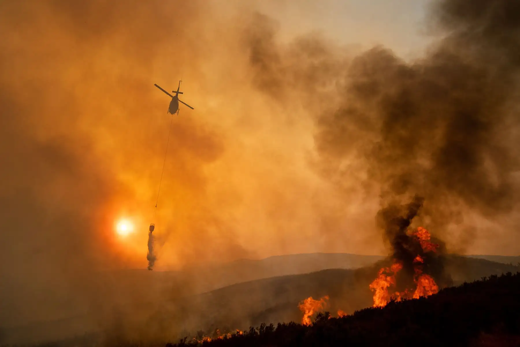 Un helicóptero arroja agua mientras lucha contra el incendio Ranch, parte del incendio complejo de Mendocino, cerca de Clearlake Oaks, California. AFP