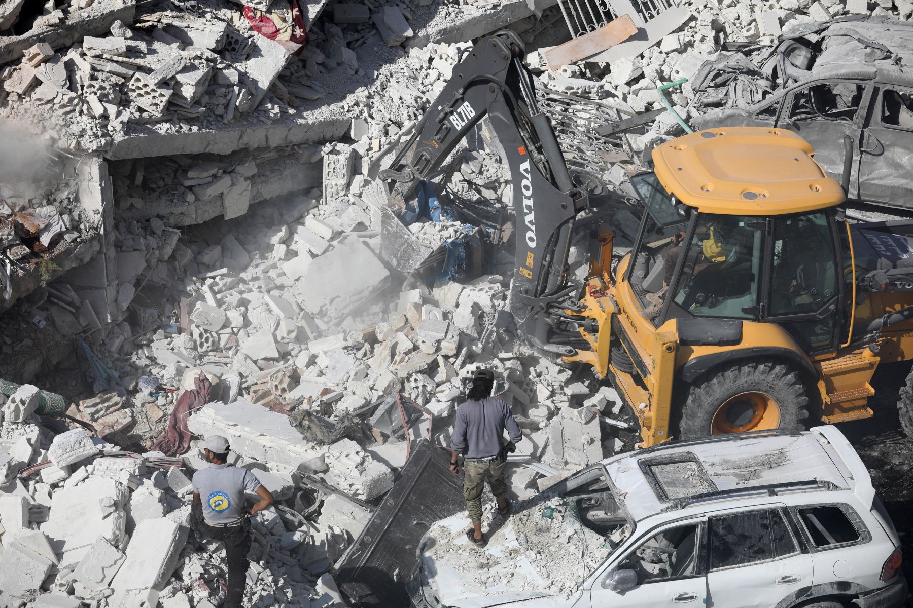 Un tractor despeja los escombros de los edificios destruidos, después de una explosión en un depósito de armas en una zona residencial en la ciudad de Sarmada, en el norte de Siria, en Idlib, donde decenas de personas murieron. / AFP