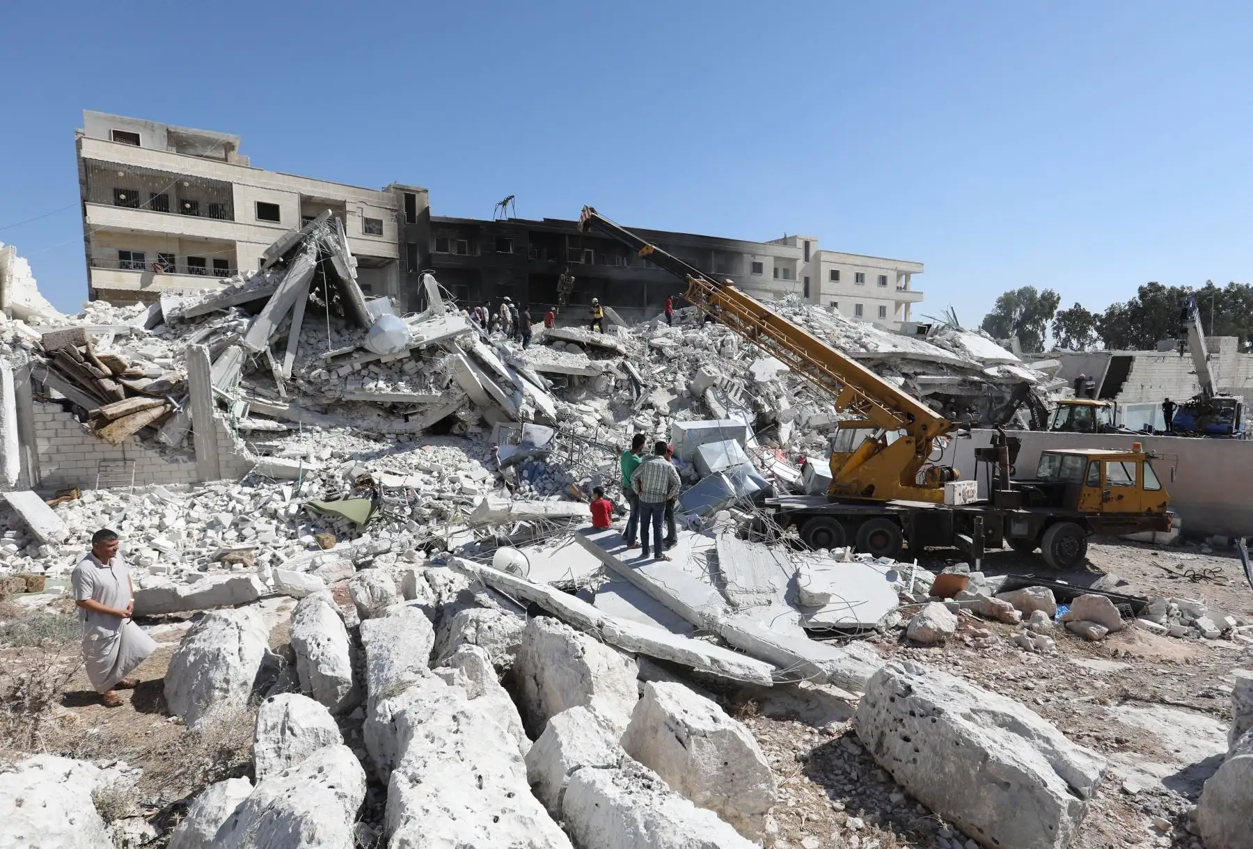 Un tractor despeja los escombros de los edificios destruidos, después de una explosión en un depósito de armas en una zona residencial en la ciudad de Sarmada, en el norte de Siria, en Idlib, donde decenas de personas murieron. / AFP