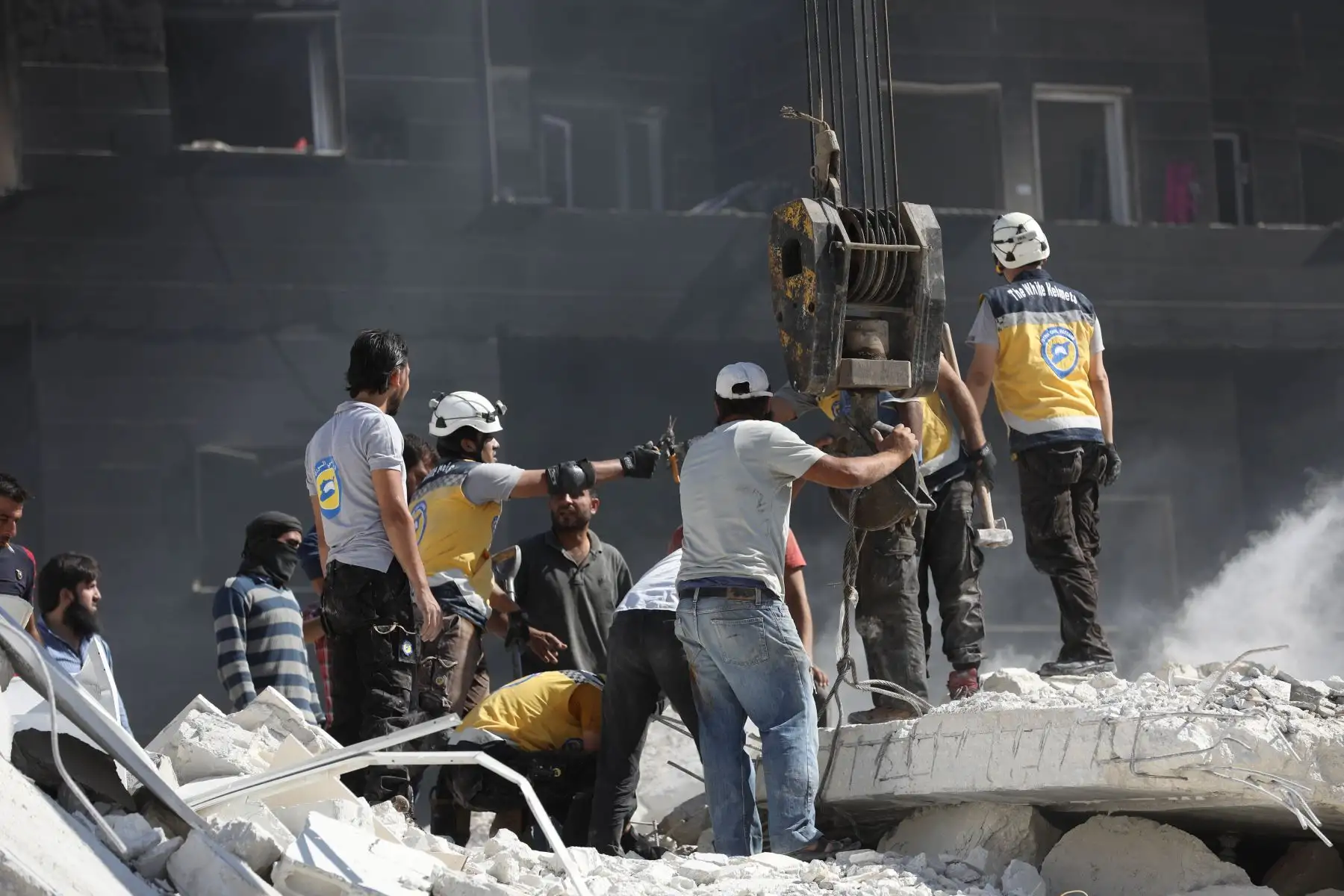 El personal de rescate, conocido como White Helmets revisa los escombros de los edificios destruidos, tras una explosión en un depósito de armas en una zona residencial en la ciudad de Sarmada en la norteña Siria de Idlib, en la que docenas de personas supuestamente asesinado. / AFP